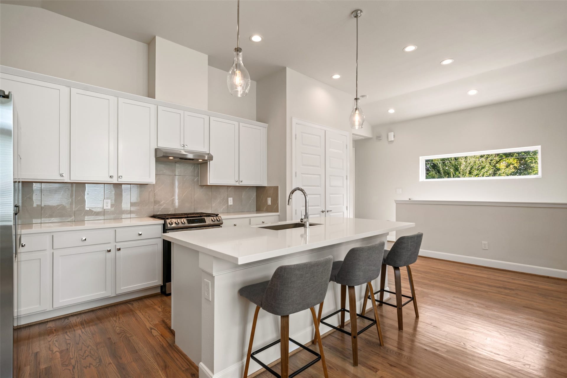 502 W Donovan Street, #A, Houston, TX 77091 Quartz island with seating for three, white shaker cabinets, gas range, and stainless appliances. The refrigerator stays.