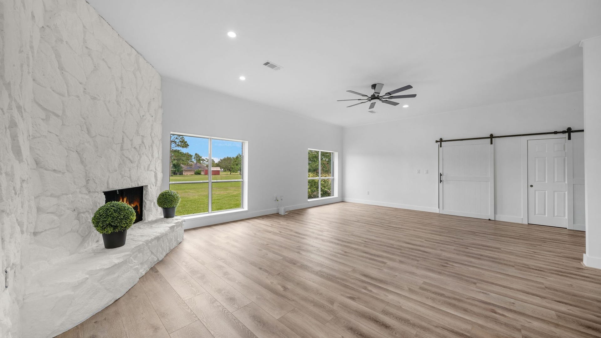 15502 Kitty Hawk Drive, Waller, TX 77484 Family Room with wood burning fireplace, Barn doors closing off leads to Primary Bedroom hall and hall of 2 secondary bedrooms and bath