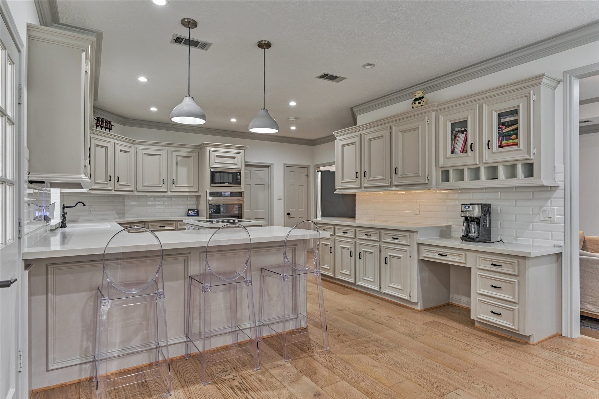 42 Golden Shadow Circle, The Woodlands, TX 77381 A striking chefs kitchen showcases updated quartz countertops, a built-in prep desk, and an expansive island with dining bar seating.