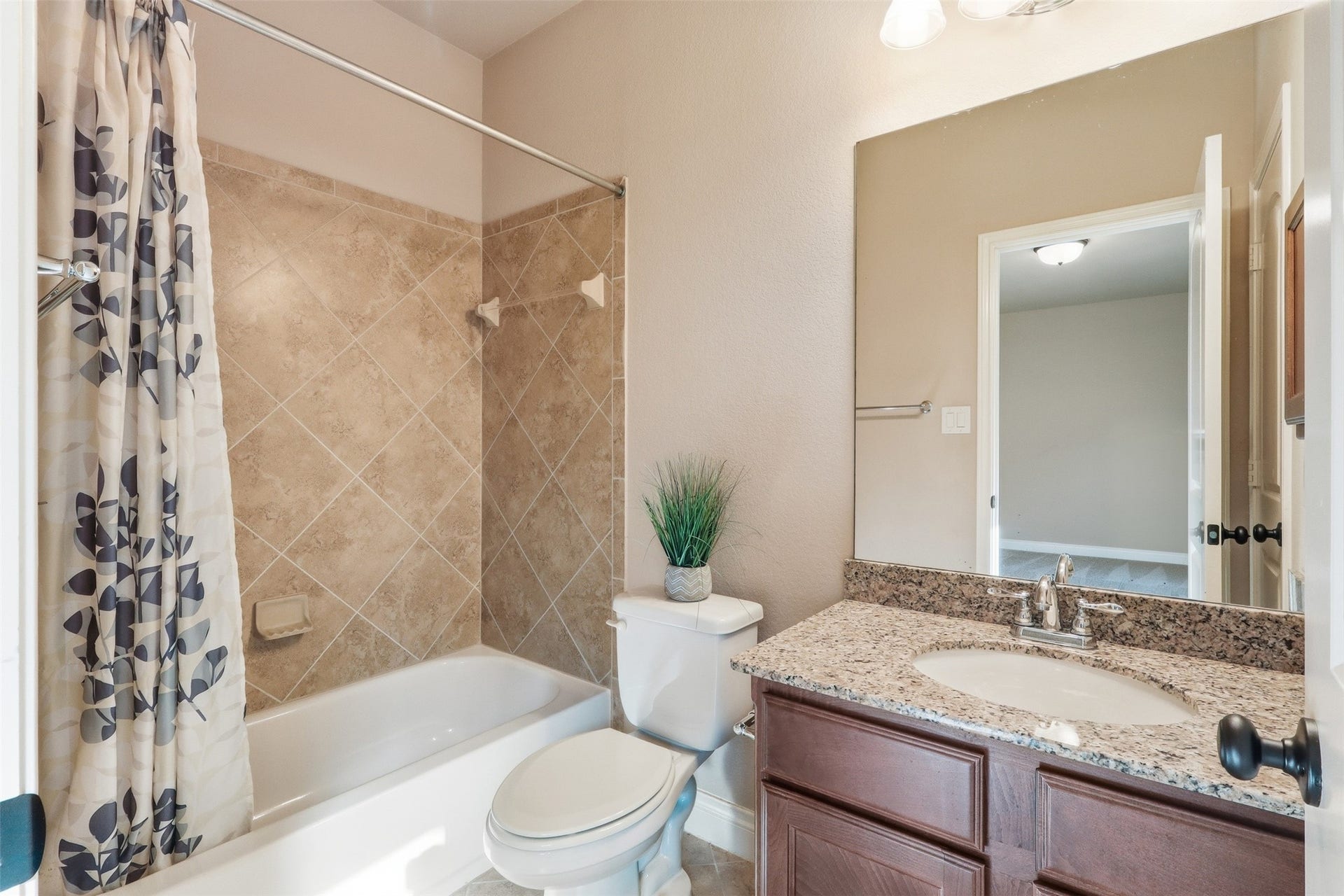 4130 Clover Ridge Lane, Sugar Land, TX 77479 This secondary primary bathrrom has a modern design with a granite countertop, a single sink and a wooden vanity. It includes a tub-shower combo with tile surround. The space is well-lit and connects to the secondary primary bedroom.