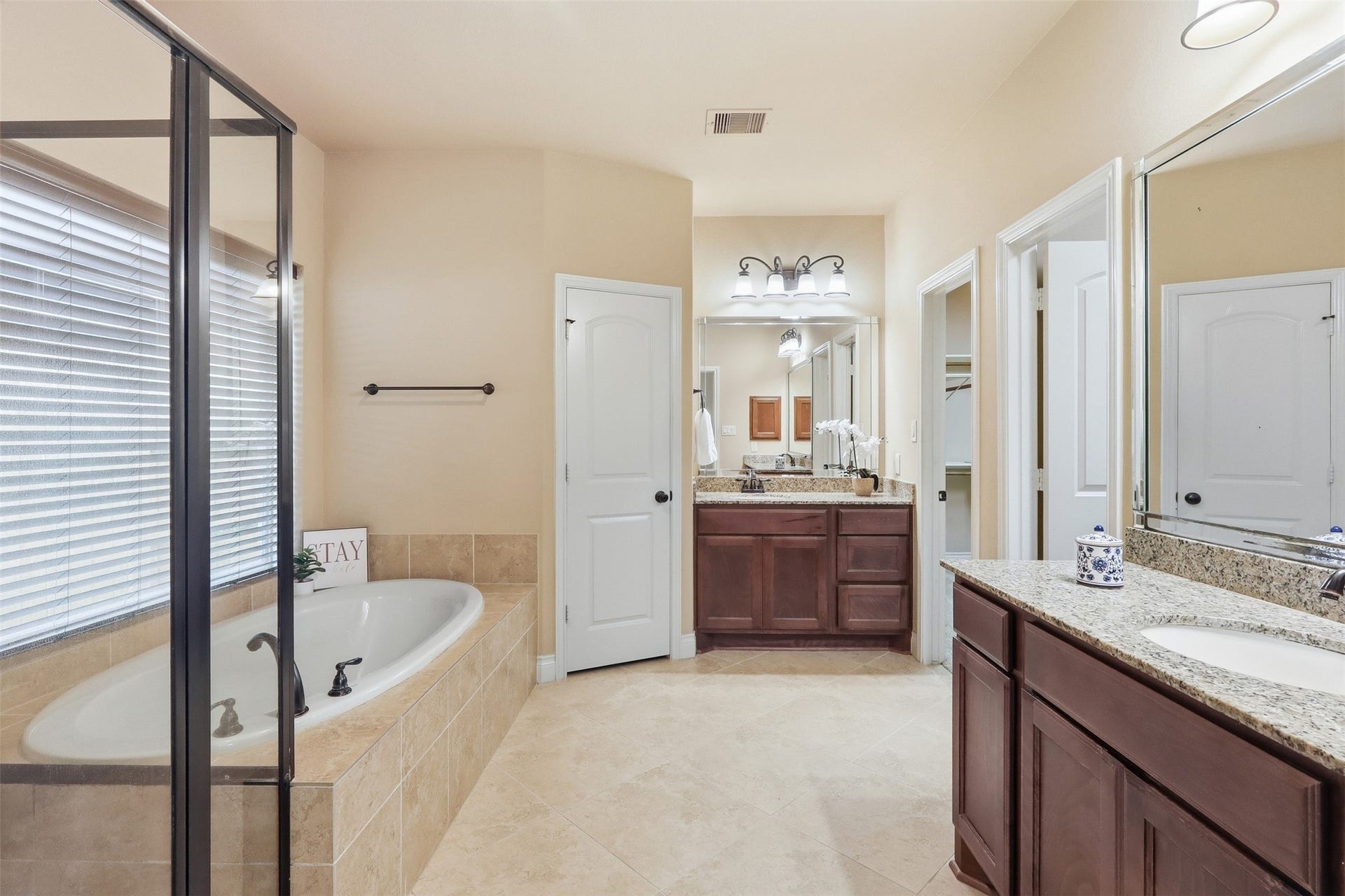4130 Clover Ridge Lane, Sugar Land, TX 77479 The primary bathroom features a luxurious soaking tub, a glass-enclosed shower, dual granite-topped vanities and large his and her closets.