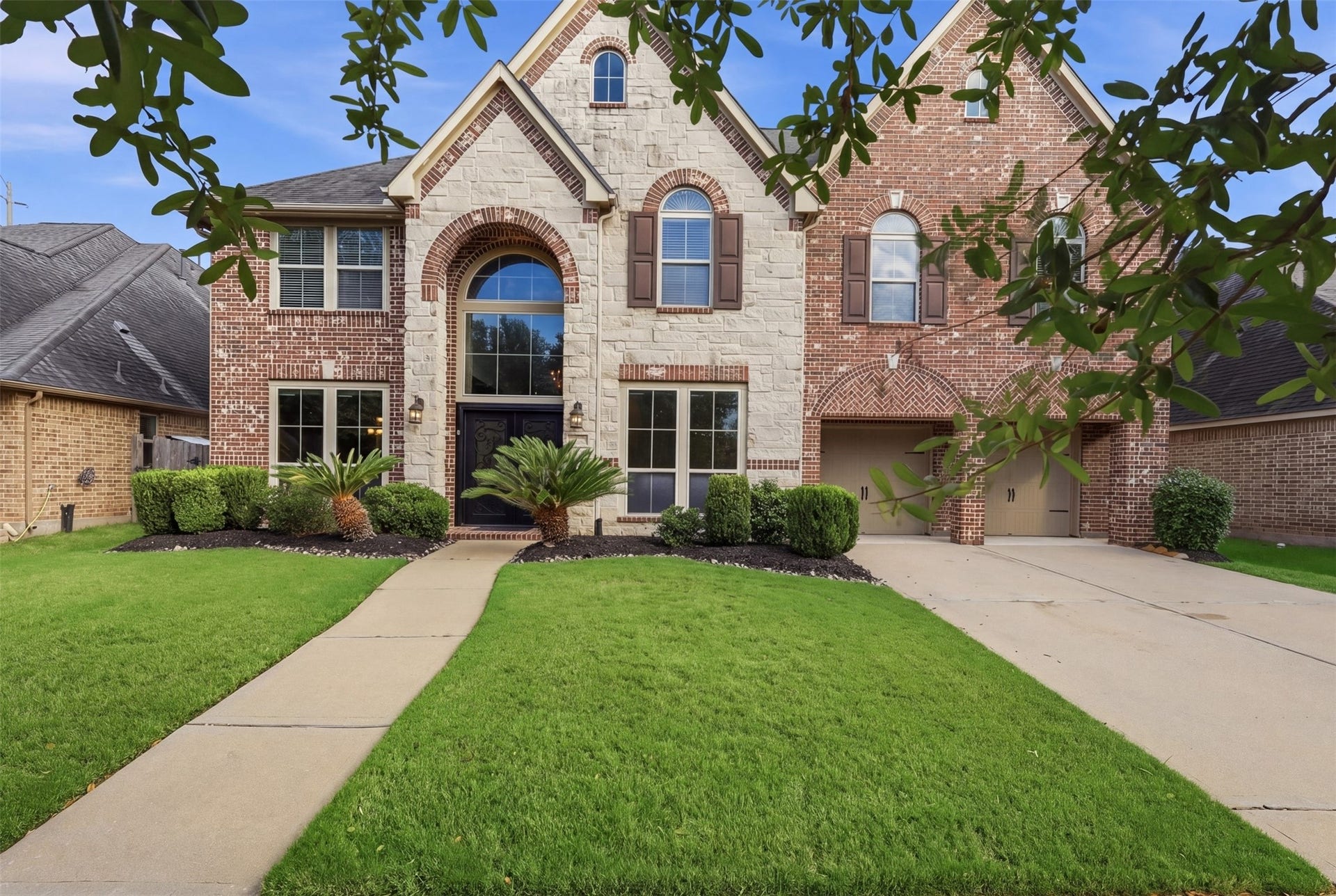 4130 Clover Ridge Lane, Sugar Land, TX 77479 This stunning two-story brick and stone Perry home features elegant arched windows, double upgraded front doors, beautifully landscaped front yard and a spacious driveway. The warm exterior lighting enhances its curb appeal.