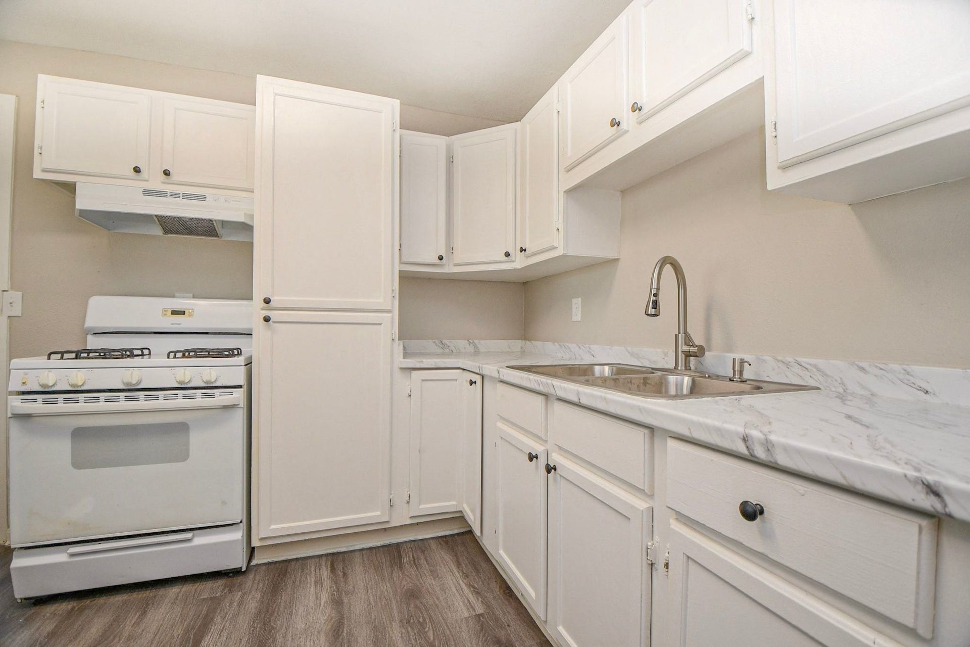 Kitchen features crisp white cabinets, marble-look countertops.