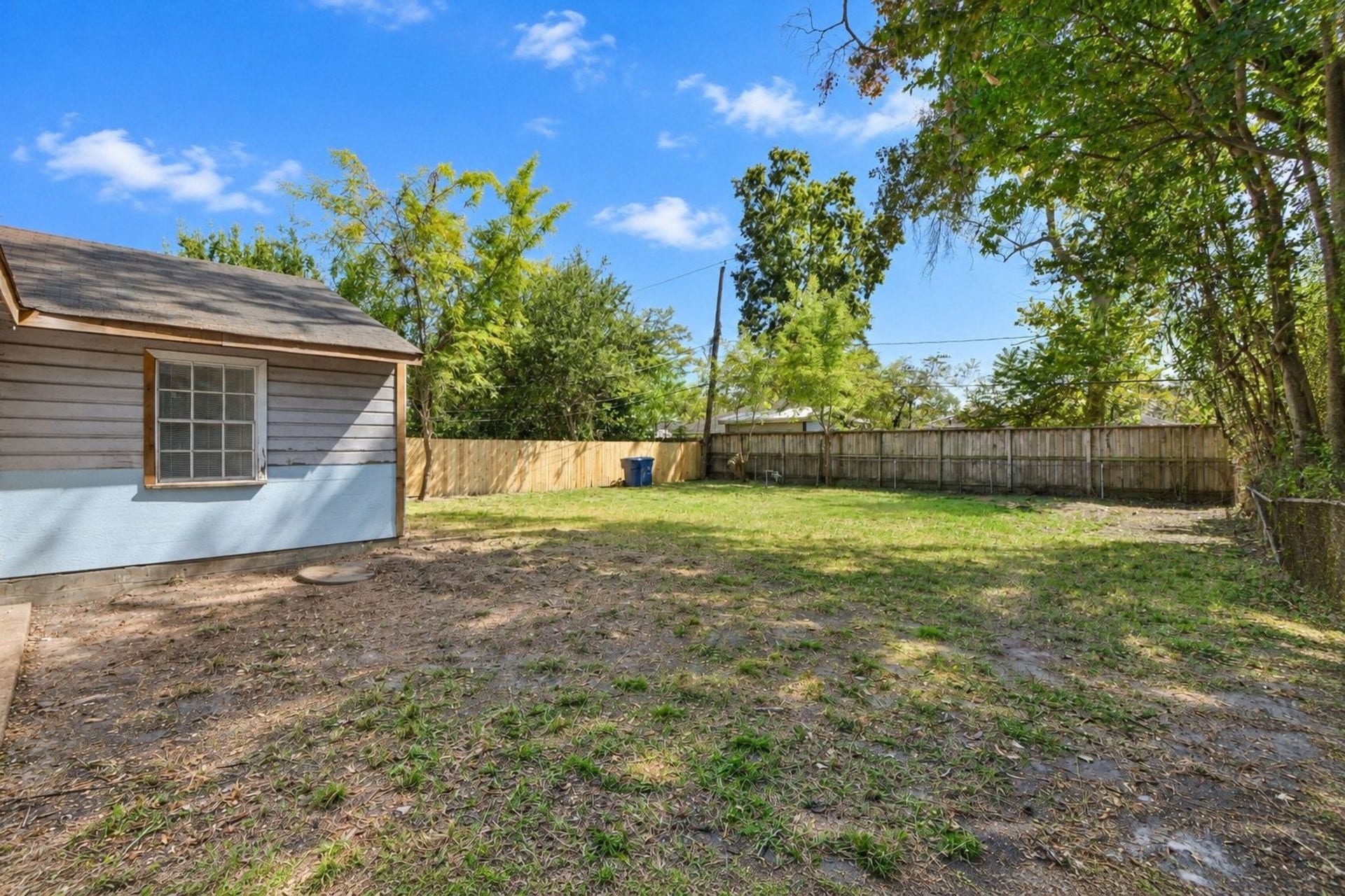 Fenced backyard with mature trees and plenty of room for outdoor activities.