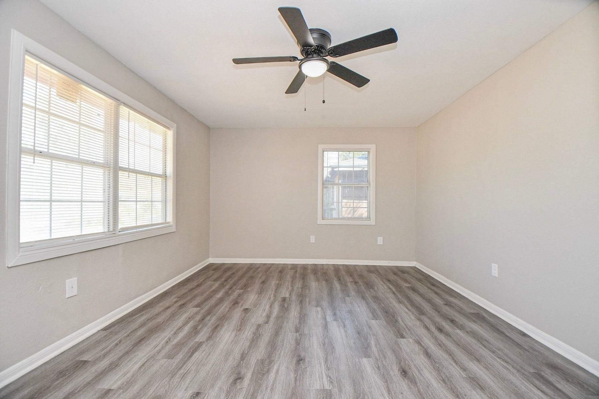 Living area features large windows that bring in natural light, complemented by a ceiling fan for added comfort and a bright, welcoming atmosphere.