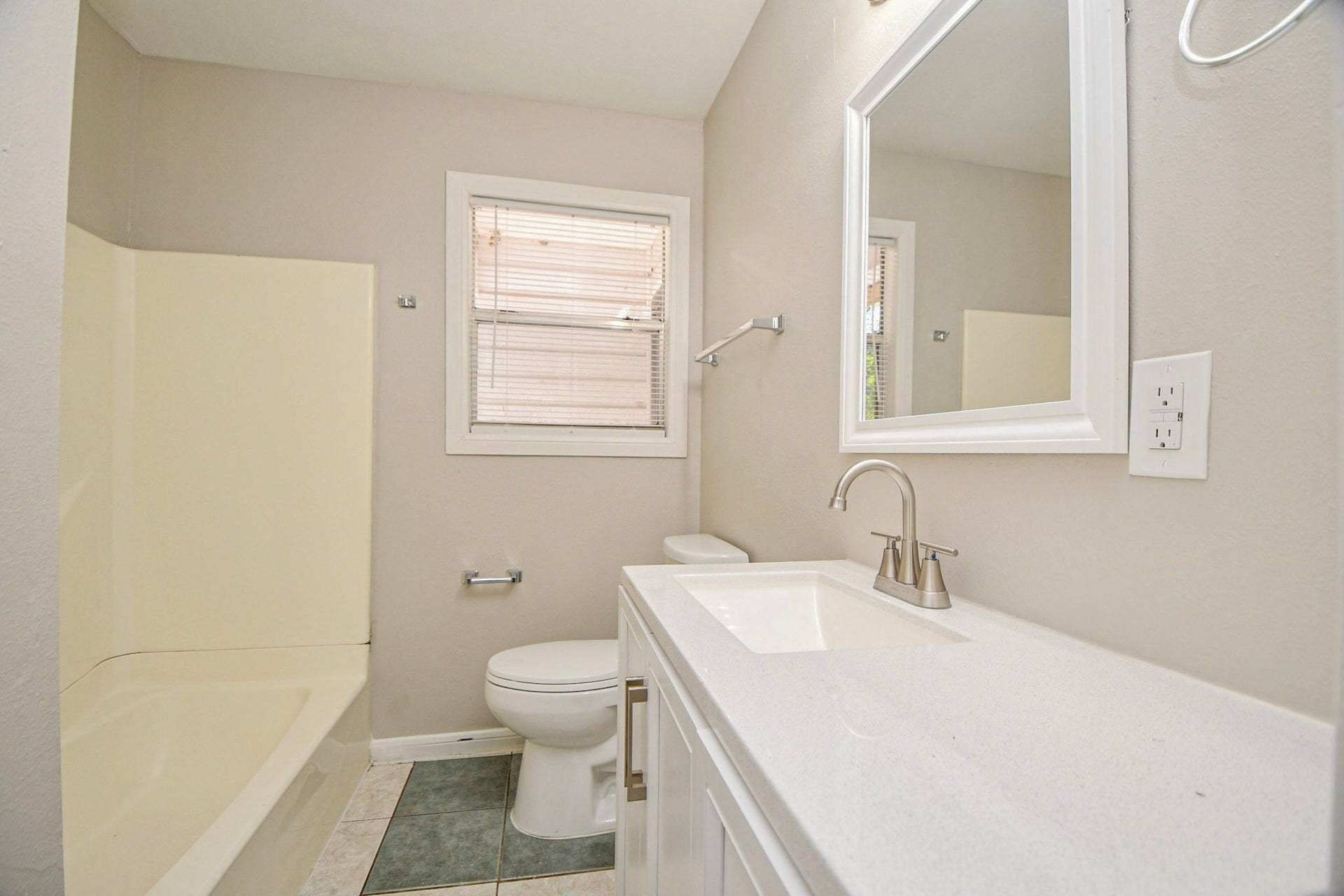 Bathroom features a clean vanity, tub/shower combination, and window for natural light.