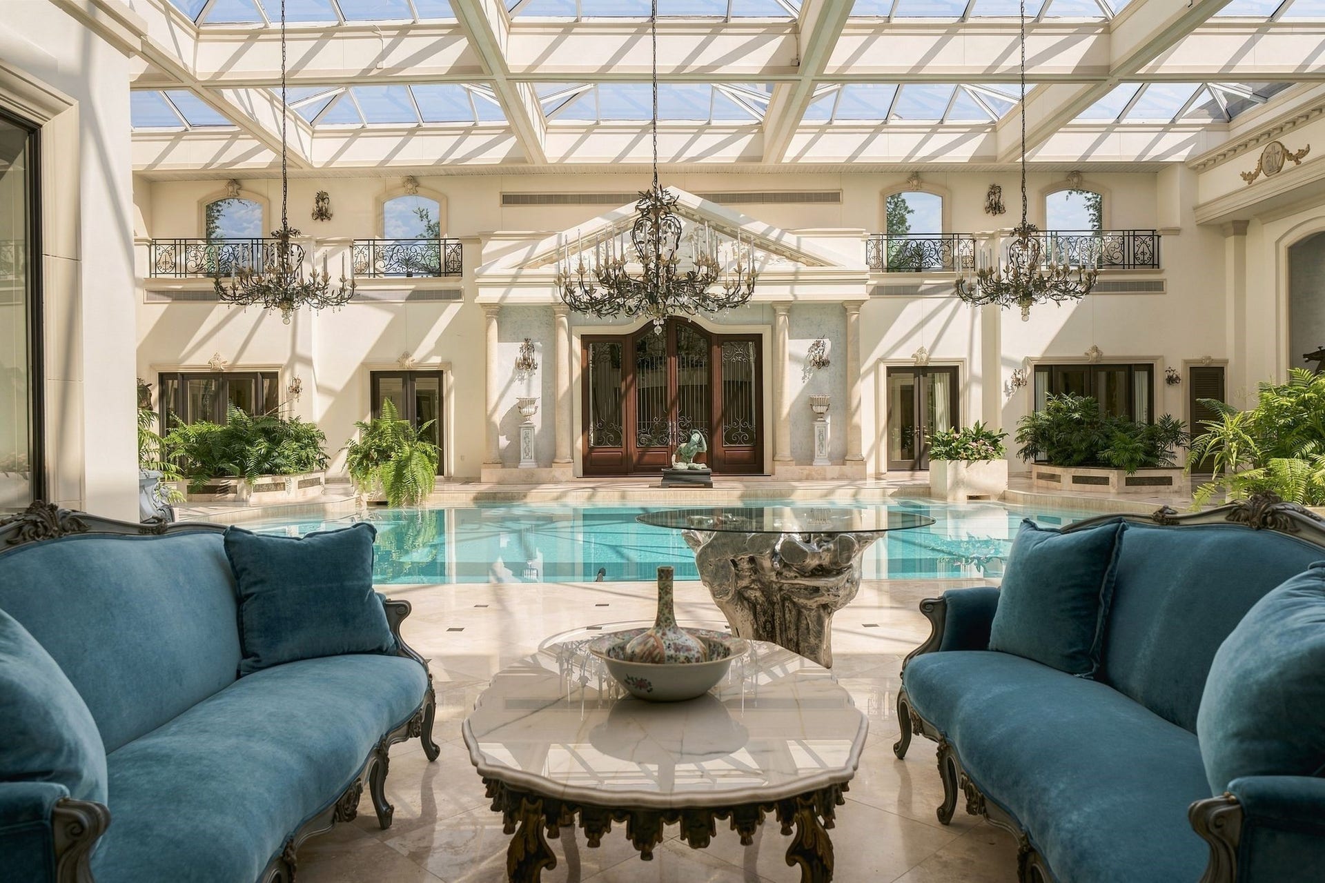 2115 River Oaks Boulevard, Houston, TX 77019 A poolside lounge looks across the water toward arched doors, grand chandeliers and the atriums upper gallery.
