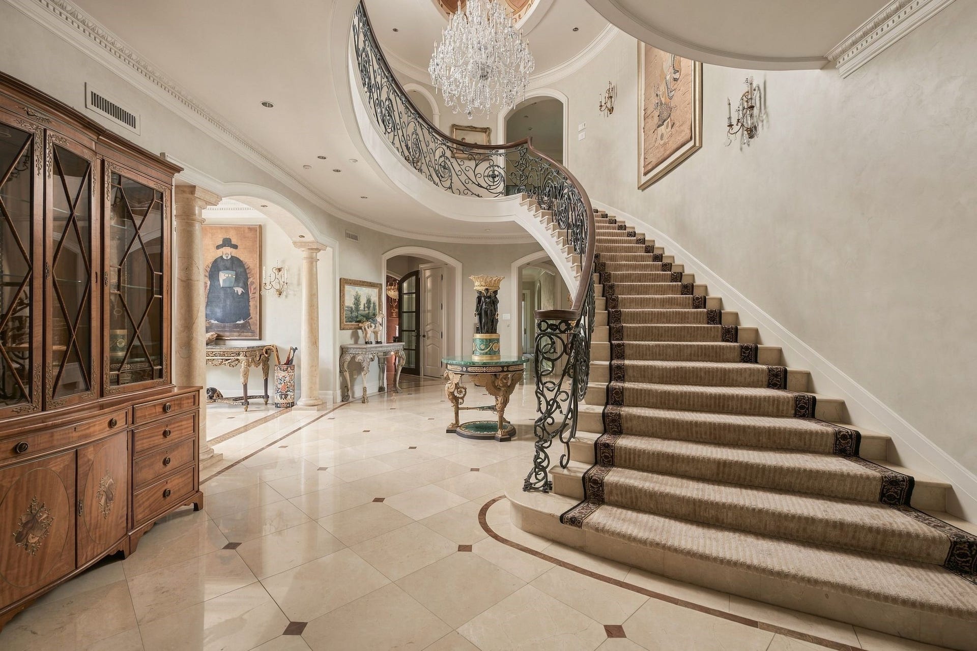 2115 River Oaks Boulevard, Houston, TX 77019 One of two sweeping staircase pairs intricate ironwork, crystal chandelier, and polished marble flooring.