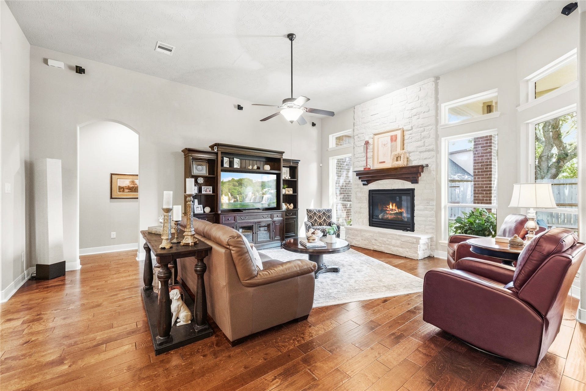 8623 Crescent Spur Drive, Richmond, TX 77406 The living room is made for gathering, featuring a fireplace, tall windows and warm hardwood floors.