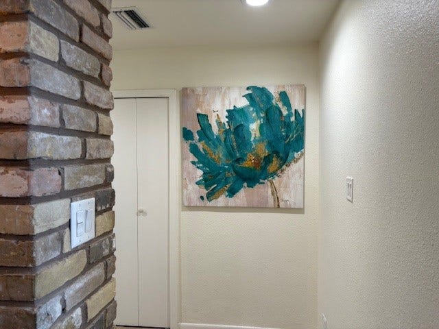 2016 Main Street, #PH 3, Houston, TX 77002 Charming hallway featuring a rustic brick accent wall and vibrant artwork, adding a touch of color and character.