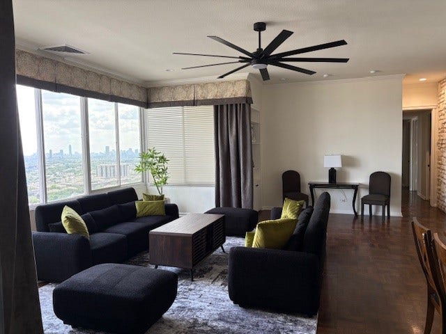 2016 Main Street, #PH 3, Houston, TX 77002 Spacious living room with modern furniture, large windows offering stunning city views, and a sleek ceiling fan.