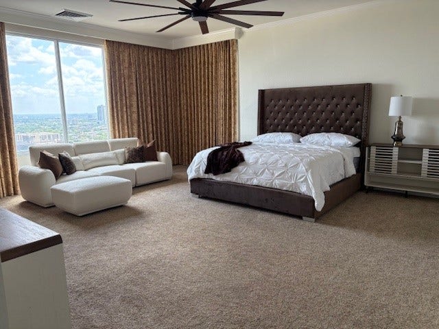 2016 Main Street, #PH 3, Houston, TX 77002 Spacious bedroom with a large window offering stunning city views, featuring a plush bed, cozy seating area, and elegant decor.