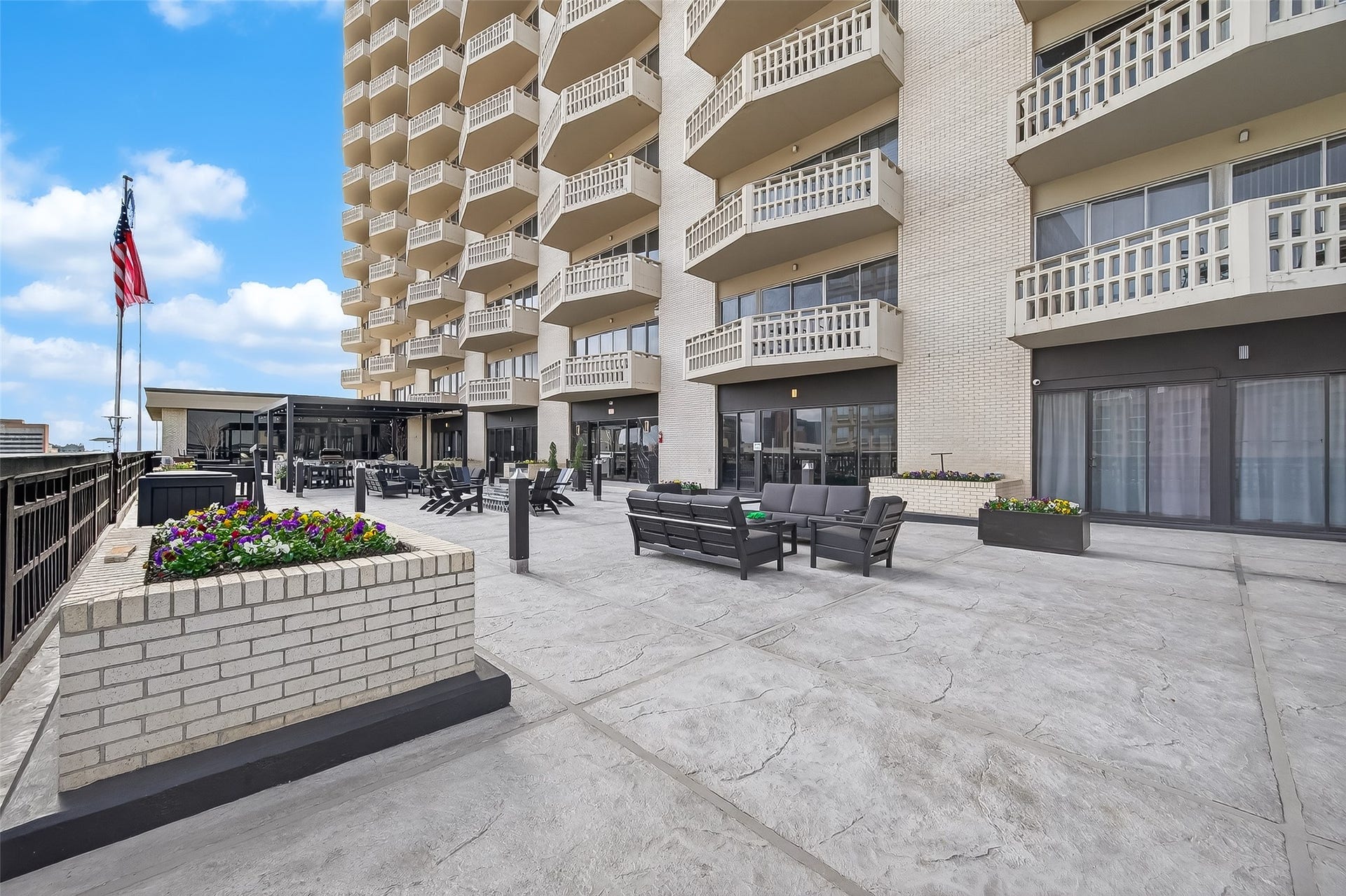 2016 Main Street, #PH 3, Houston, TX 77002 Expansive terrace with comfortable seating and vibrant planters, set against a backdrop of a modern building with private balconies.