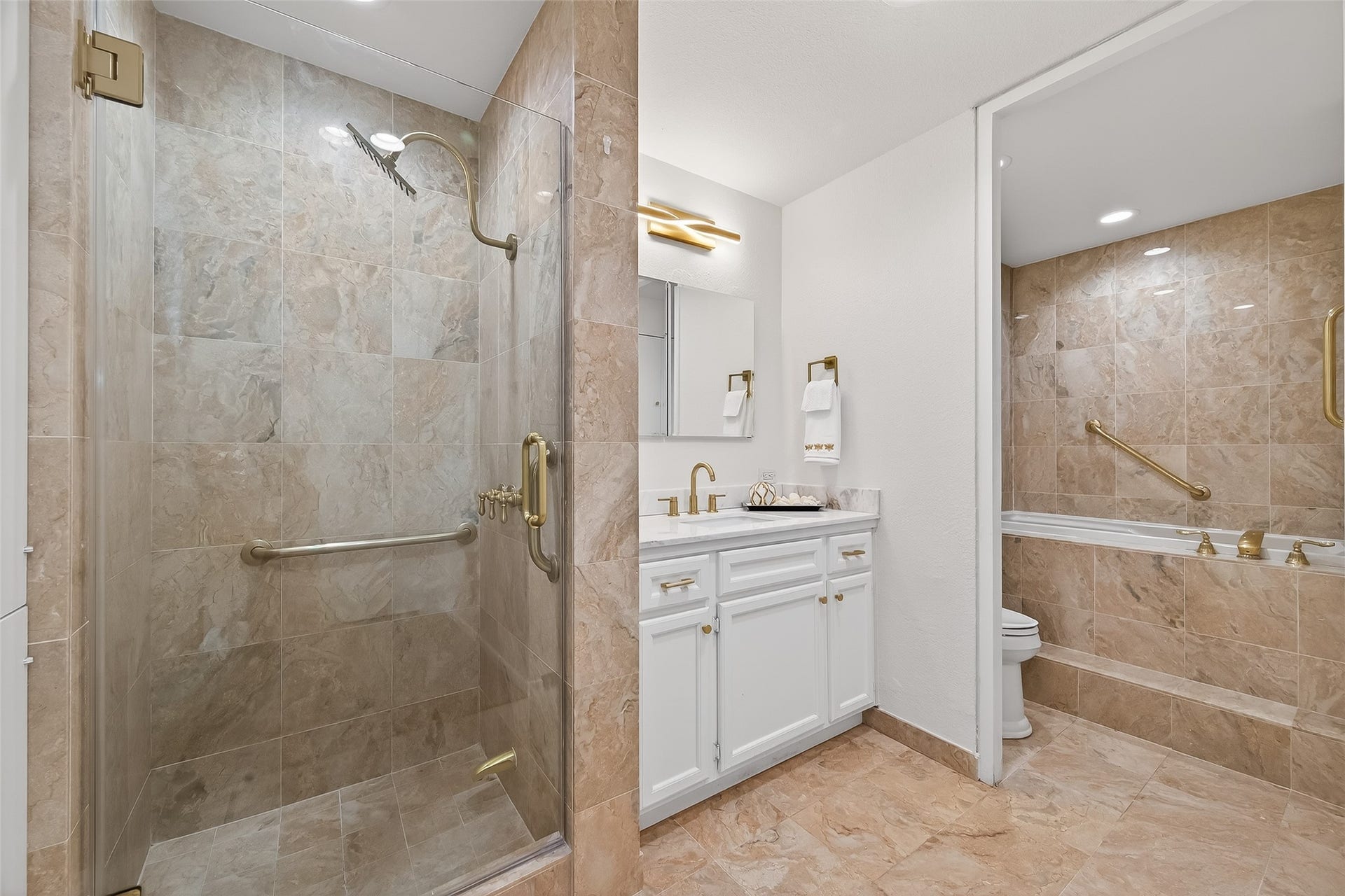 2016 Main Street, #PH 3, Houston, TX 77002 Luxurious bathroom featuring elegant marble tiling, a spacious glass-enclosed shower, and a cozy soaking tub for ultimate relaxation.
