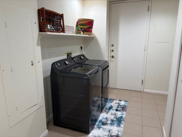 2016 Main Street, #PH 3, Houston, TX 77002 Modern laundry area with sleek black appliances, built-in shelving, and convenient tile flooring, offering functionality and style.