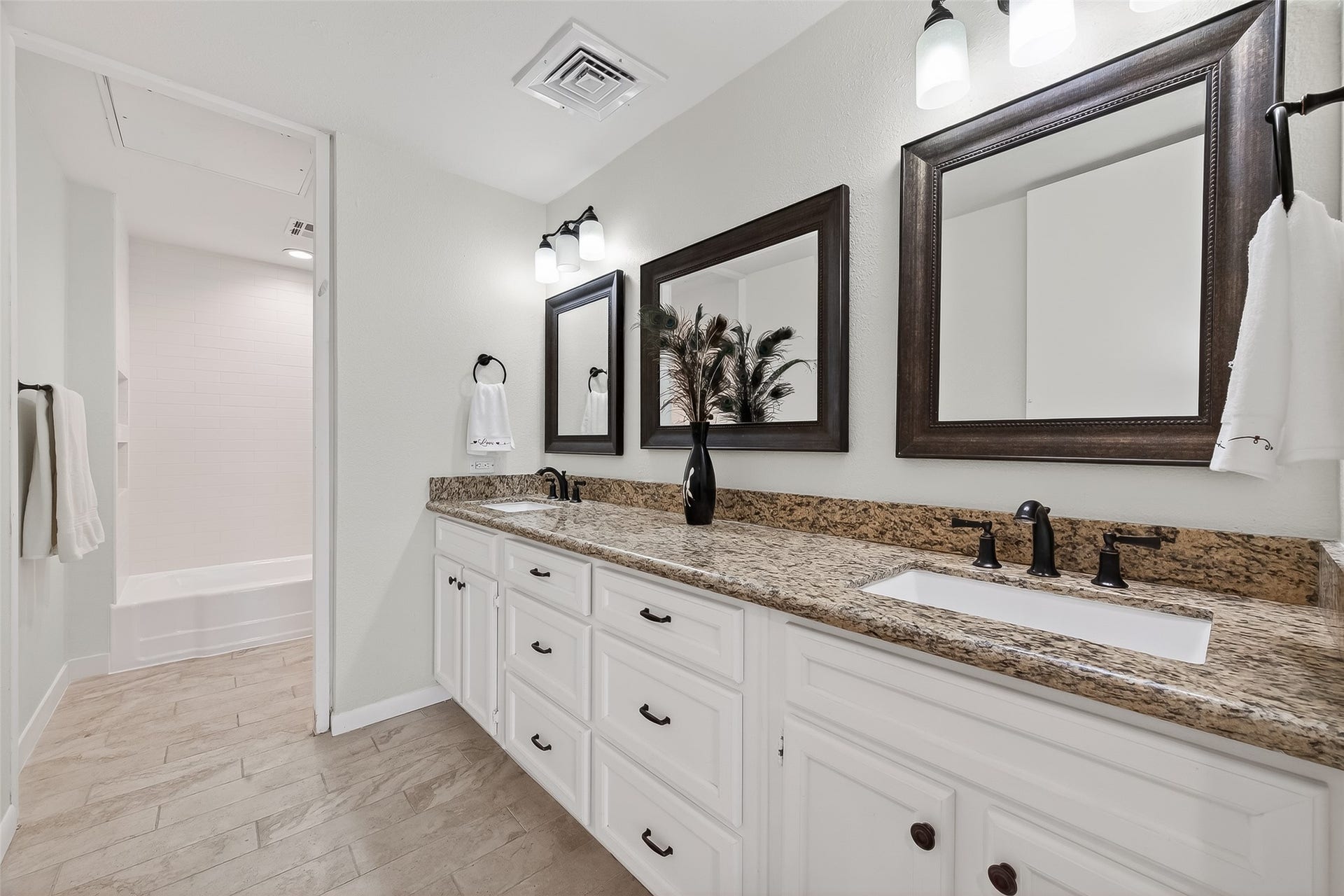 2016 Main Street, #PH 3, Houston, TX 77002 Elegant bathroom featuring a granite double vanity with dark fixtures, complemented by framed mirrors and sleek lighting.