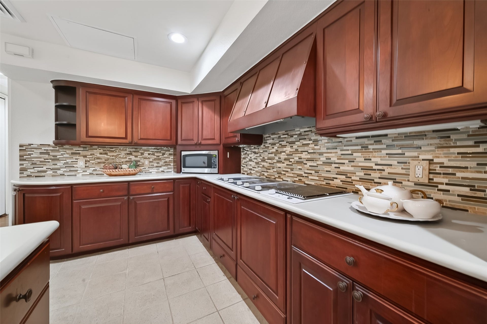 2016 Main Street, #PH 3, Houston, TX 77002 Elegant kitchen featuring rich wooden cabinetry, sleek countertops, and a stylish mosaic tile backsplash, creating a warm and inviting cooking space.