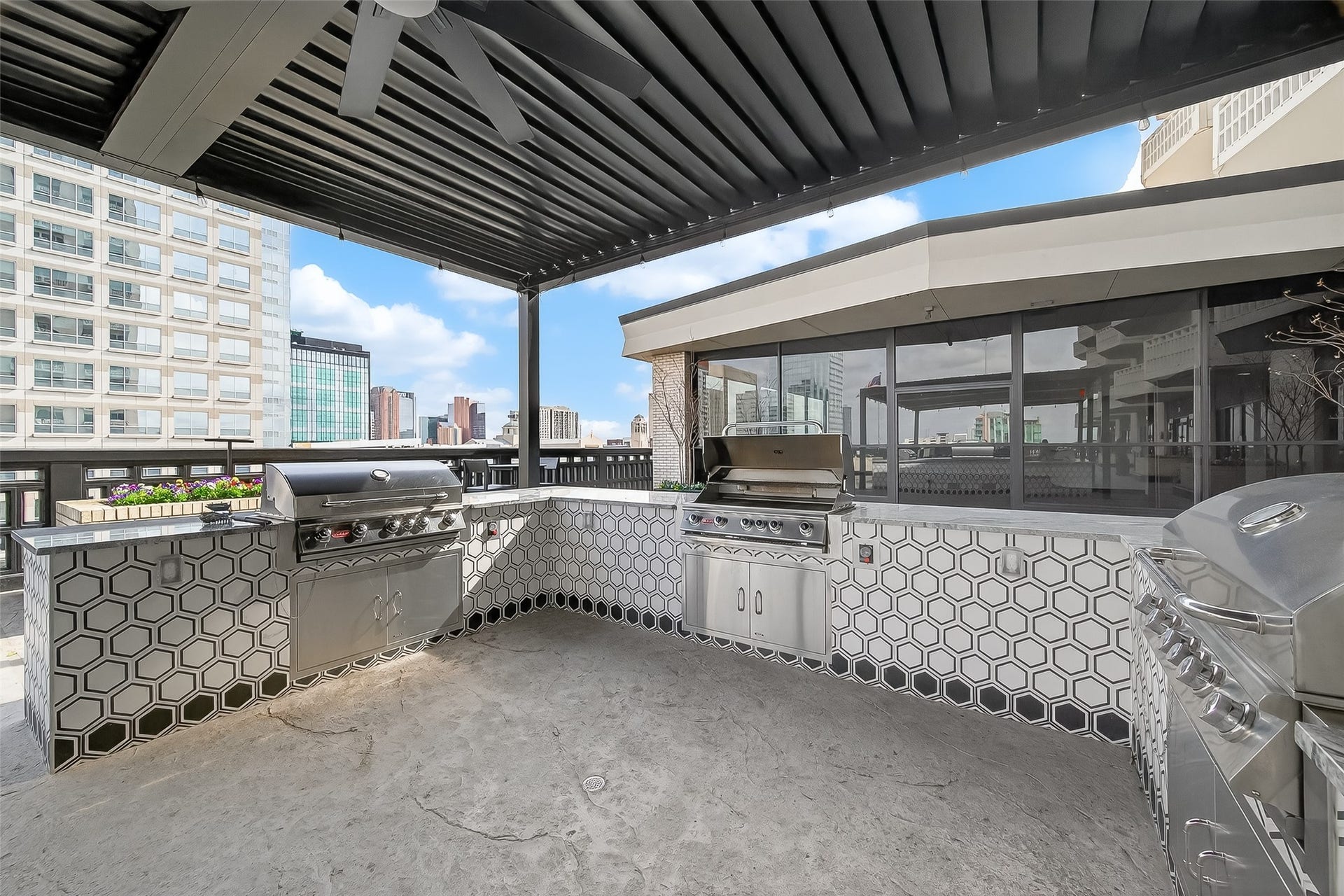 2016 Main Street, #PH 3, Houston, TX 77002 Experience luxury outdoor living with this stylish rooftop terrace featuring a sleek built-in grill station, modern hexagon tile accents, and expansive city views. Perfect for entertaining.