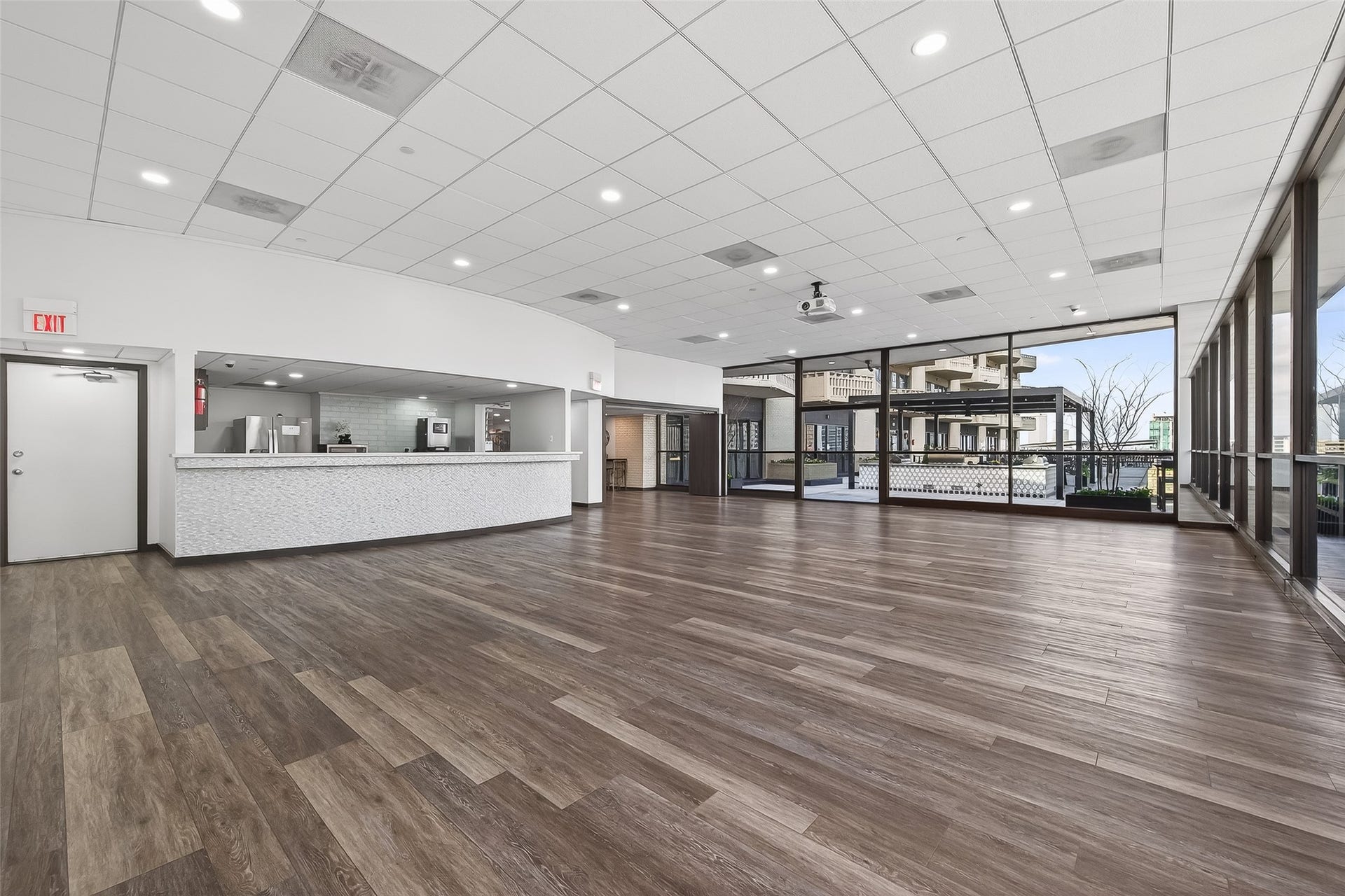 2016 Main Street, #PH 3, Houston, TX 77002 Spacious multi-purpose room with sleek hardwood floors, modern ceiling lighting, and expansive glass windows offering abundant natural light. Features an open kitchen area with a contemporary design, perfect for entertaining or events.