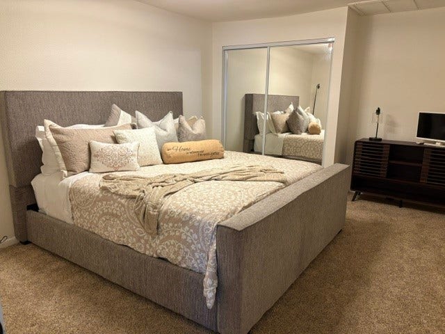 2016 Main Street, #PH 3, Houston, TX 77002 Cozy bedroom featuring a plush upholstered bed with elegant bedding, mirrored closet doors, and a compact entertainment unit for a comfortable retreat.