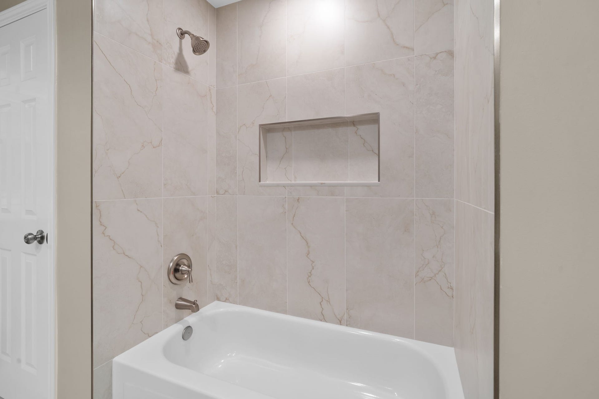 The beautifully updated tub & shower surround features large-format tile carried to the ceiling with a generous built-in niche for a clean, polished finish.