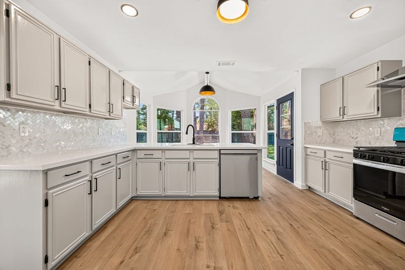 Bright and spacious kitchen with modern cabinetry, sleek stainless steel appliances, and a large window offering plenty of natural light.