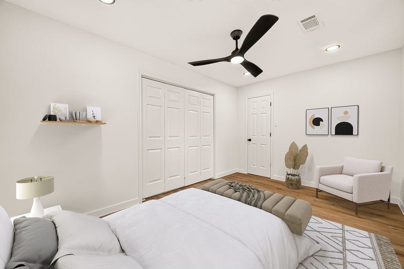 Bright and airy bedroom featuring sleek hardwood floors, a modern ceiling fan, and ample closet space, accented by minimalist decor.