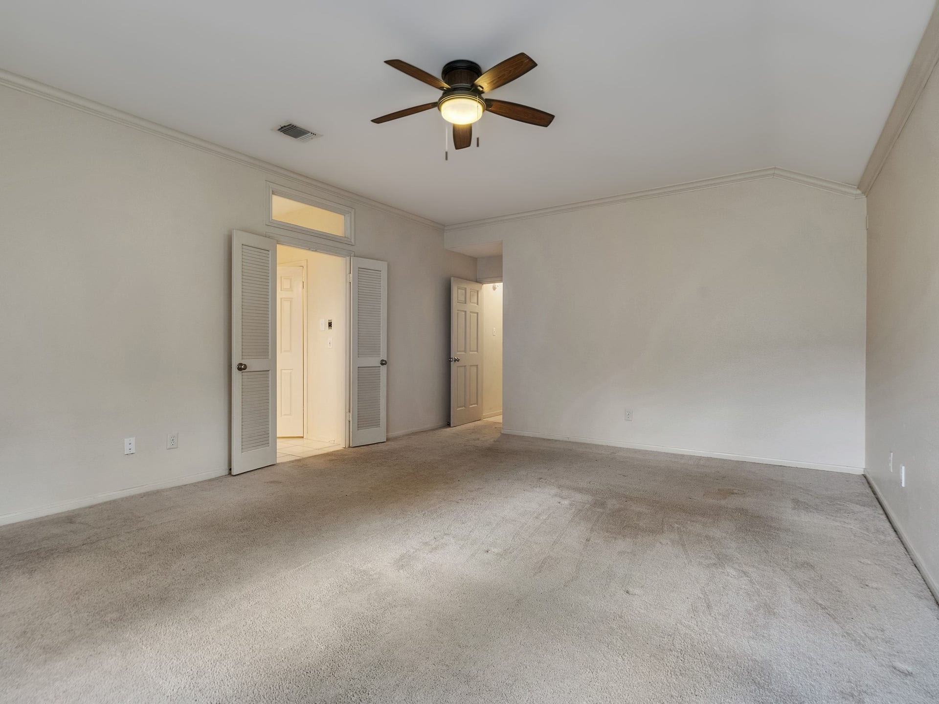 View of the primary bedroom with a transom window over the double doors leading to the bathroom