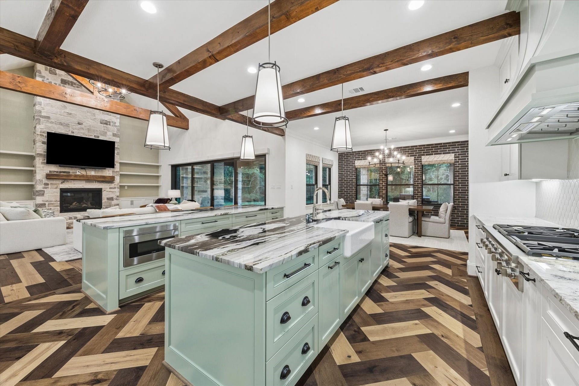 The oversized gathering island provides generous seating and serves as the social heart of this exceptional chefs kitchen. Fantasy Zebra marble introduces dramatic natural movement, while custom sage-green cabinetry and rich wood ceiling beams add warmth and character. The kitchen also features paneled appliance integration, two refrigerators with freezers, two dishwashers, double ovens, a warming drawer, built-in microwave, and an impressive six-burner Thermador cooktop with integrated griddle.