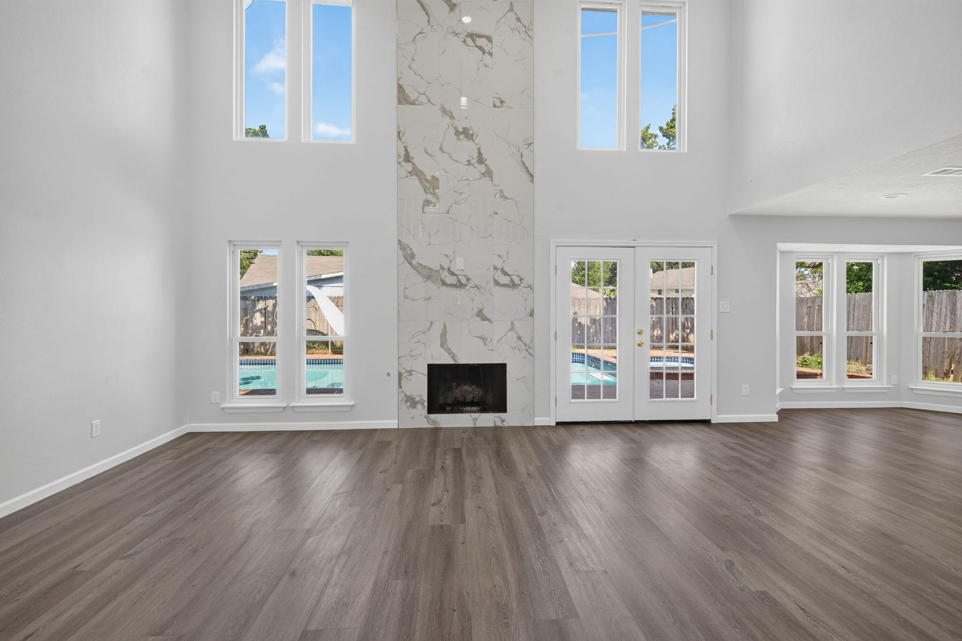 1123 Mayweather Lane, Richmond, TX 77406 Soaring ceilings and a dramatic floor-to-ceiling fireplace create a stunning centerpiece, while walls of windows bring the backyard and pool views indoors.