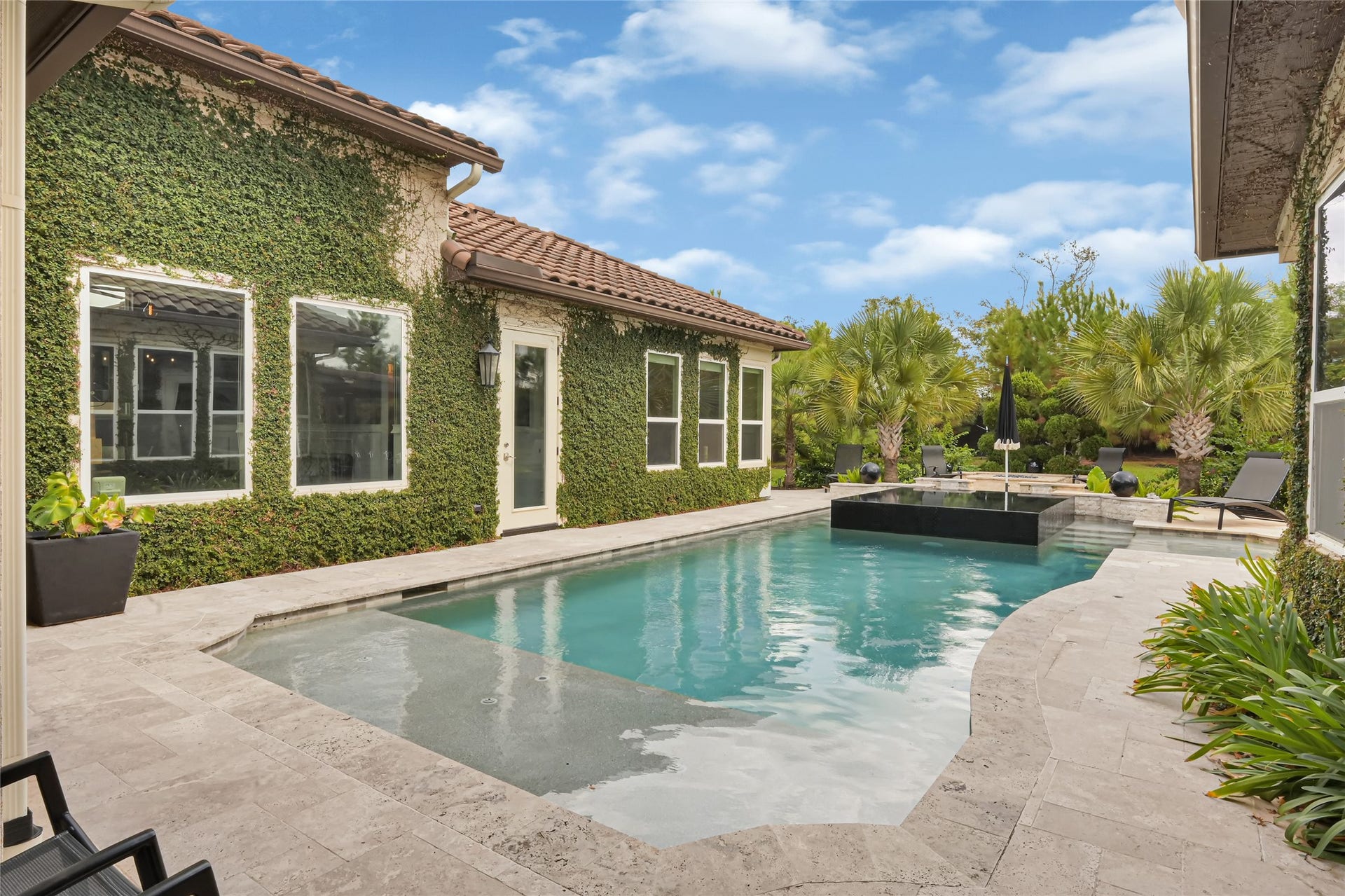 23610 Thortons Park Lane, Spring, TX 77389 Stunning custom pool featuring elegant black glass tile accents and high-end travertine decking.