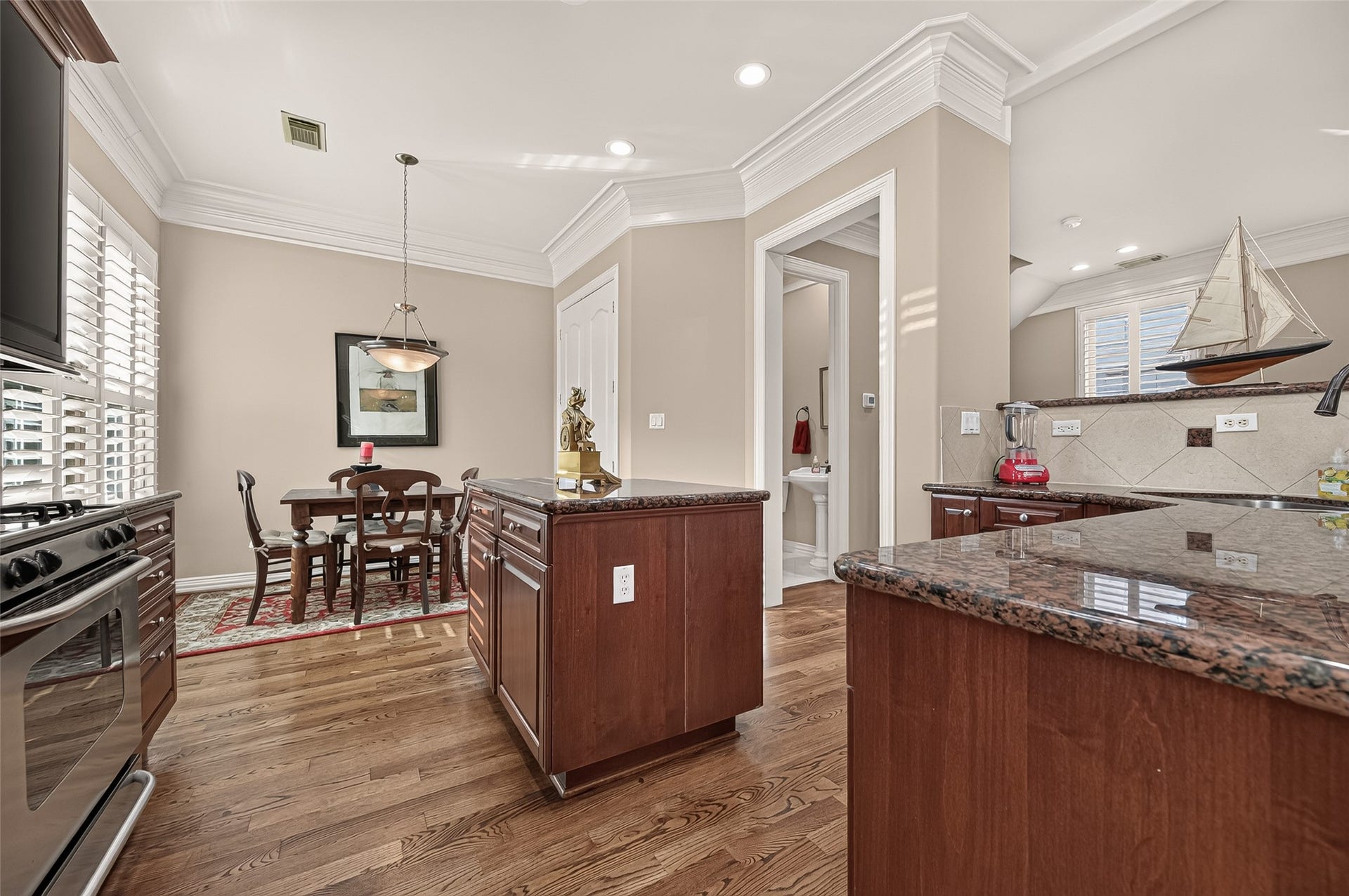 4003 Bellefontaine Street, Houston, TX 77025 Beautifully appointed kitchen featuring rich wood cabinetry, granite countertops, a center island and stainless steel appliances. Hardwood floors, crown molding and plantation shutters complement the adjoining breakfast area, creating an inviting space for everyday dining.