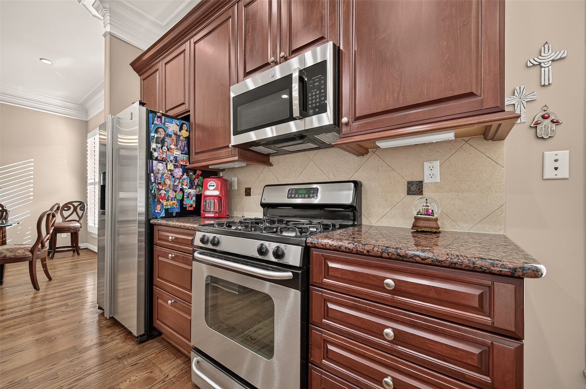 4003 Bellefontaine Street, Houston, TX 77025 Well-appointed kitchen featuring rich wood cabinetry, granite countertops, a tile backsplash, and stainless steel appliances, including a gas range and new built-in microwave. Hardwood floors and an adjoining breakfast area add warmth and convenience.