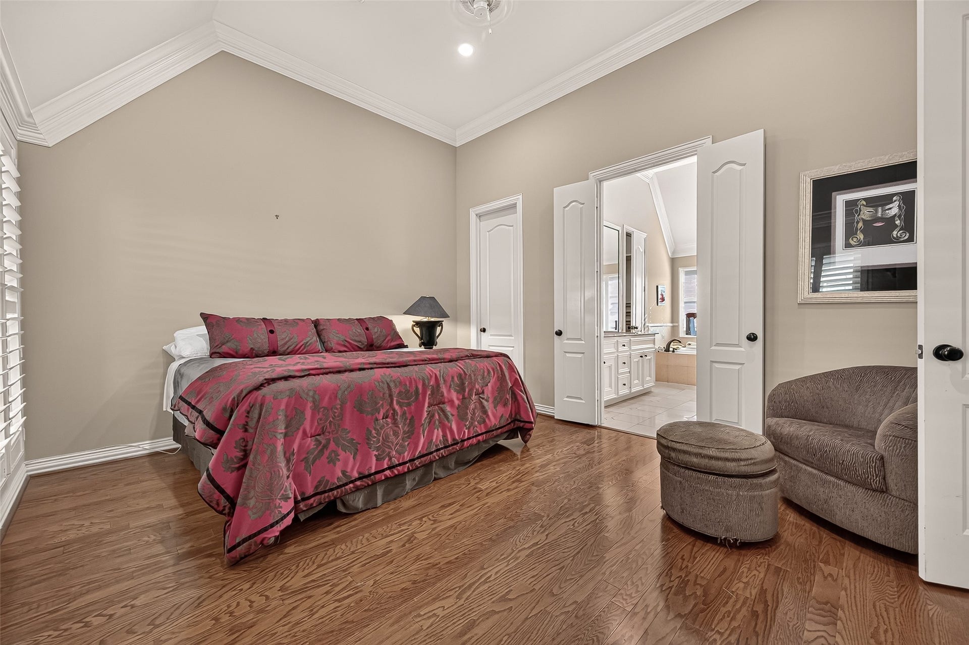 4003 Bellefontaine Street, Houston, TX 77025 A serene primary retreat with vaulted ceilings, rich hardwood floors and plantation shutters. A comfortable sitting area invites relaxation, while double doors open to the spacious ensuite bath.