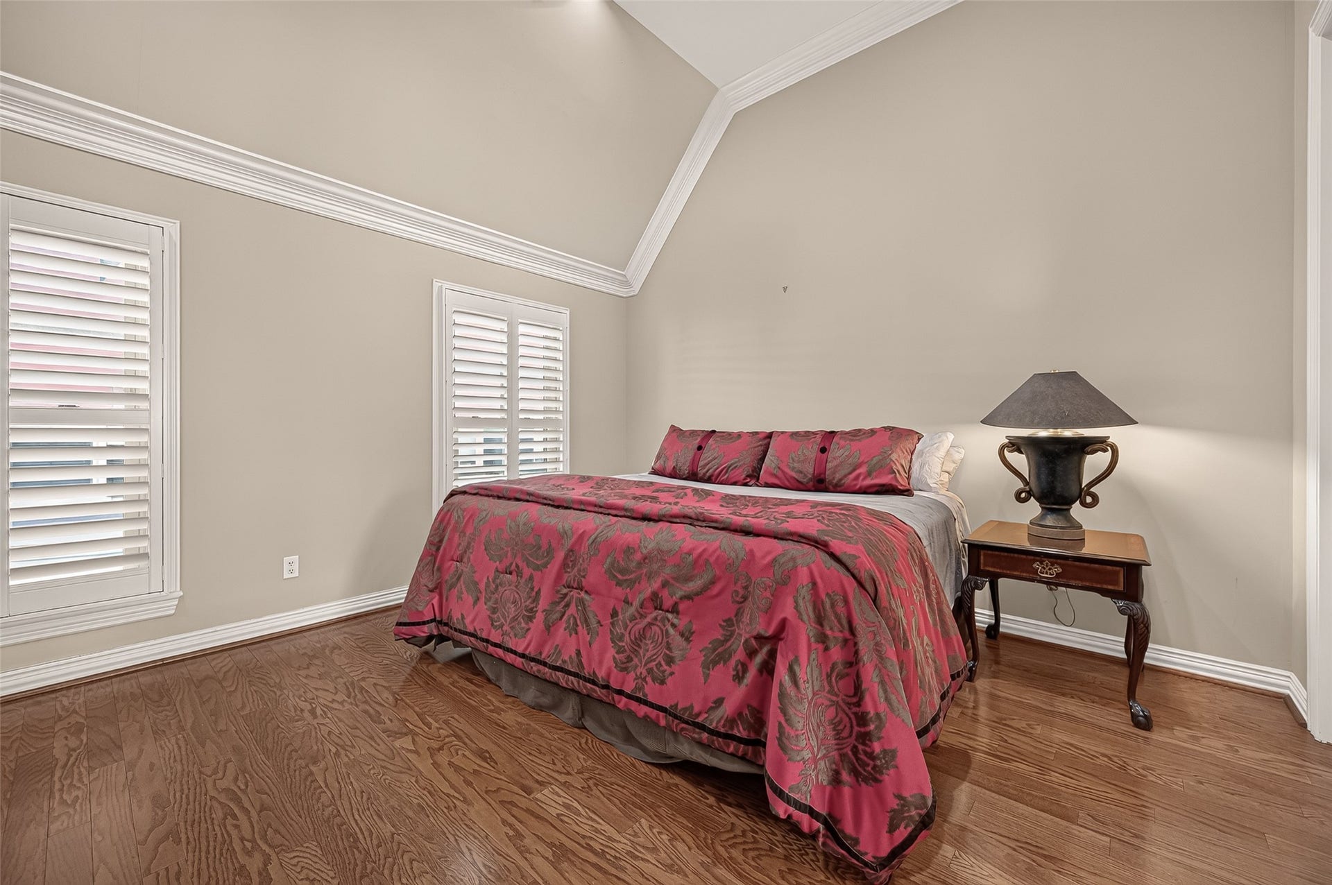 4003 Bellefontaine Street, Houston, TX 77025 Additional view of the third-floor primary bedroom, showcasing its dramatic vaulted ceiling, detailed crown molding, and rich hardwood floors. Tall windows with plantation shutters enhance the bright, restful atmosphere.