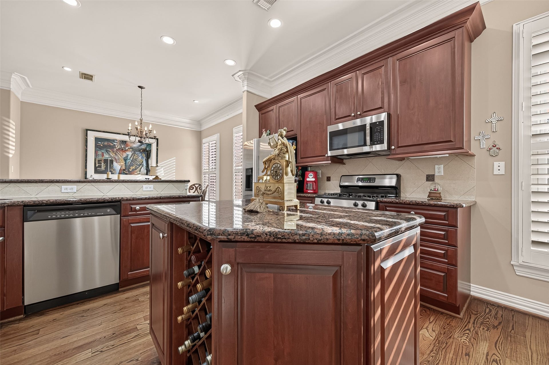4003 Bellefontaine Street, Houston, TX 77025 Well-appointed kitchen featuring rich wood cabinetry, granite countertops, a tile backsplash, and stainless steel appliances, including a gas range and built-in microwave. Hardwood floors and an adjoining breakfast area add warmth and convenience.