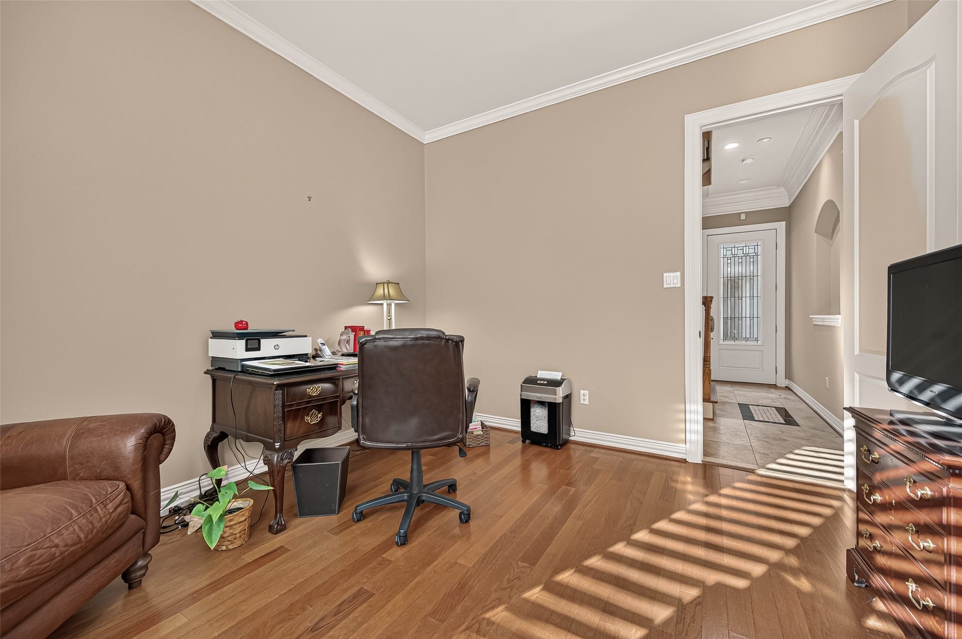 4003 Bellefontaine Street, Houston, TX 77025 Alternate view of the spacious first-floor room, showcasing wood floors, crown molding, and convenient access to the foyer. An inviting, versatile space for a home office or guest retreat.