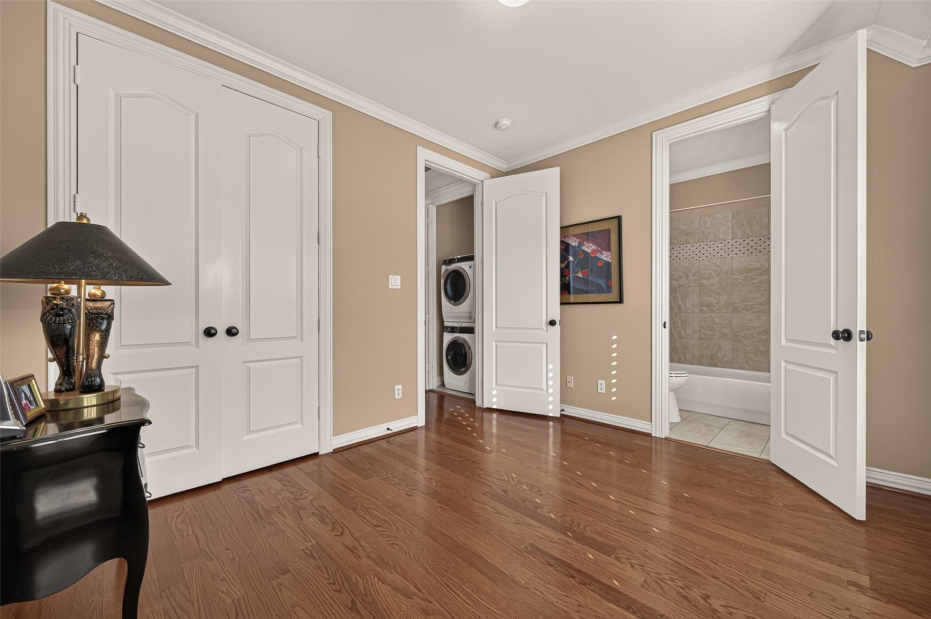 4003 Bellefontaine Street, Houston, TX 77025 Additional view of the third-floor secondary bedroom featuring hardwood floors, crown molding, and a double-door closet. An adjoining bathroom with a tub and shower combination and nearby laundry add everyday convenience.