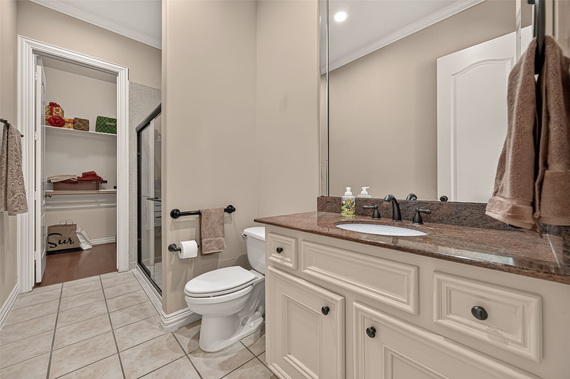 4003 Bellefontaine Street, Houston, TX 77025 First-floor en suite bathroom featuring a spacious vanity, tile flooring, and a glass-enclosed walk-in shower. An adjoining walk-in closet offers convenient storage, completing this comfortable guest suite.