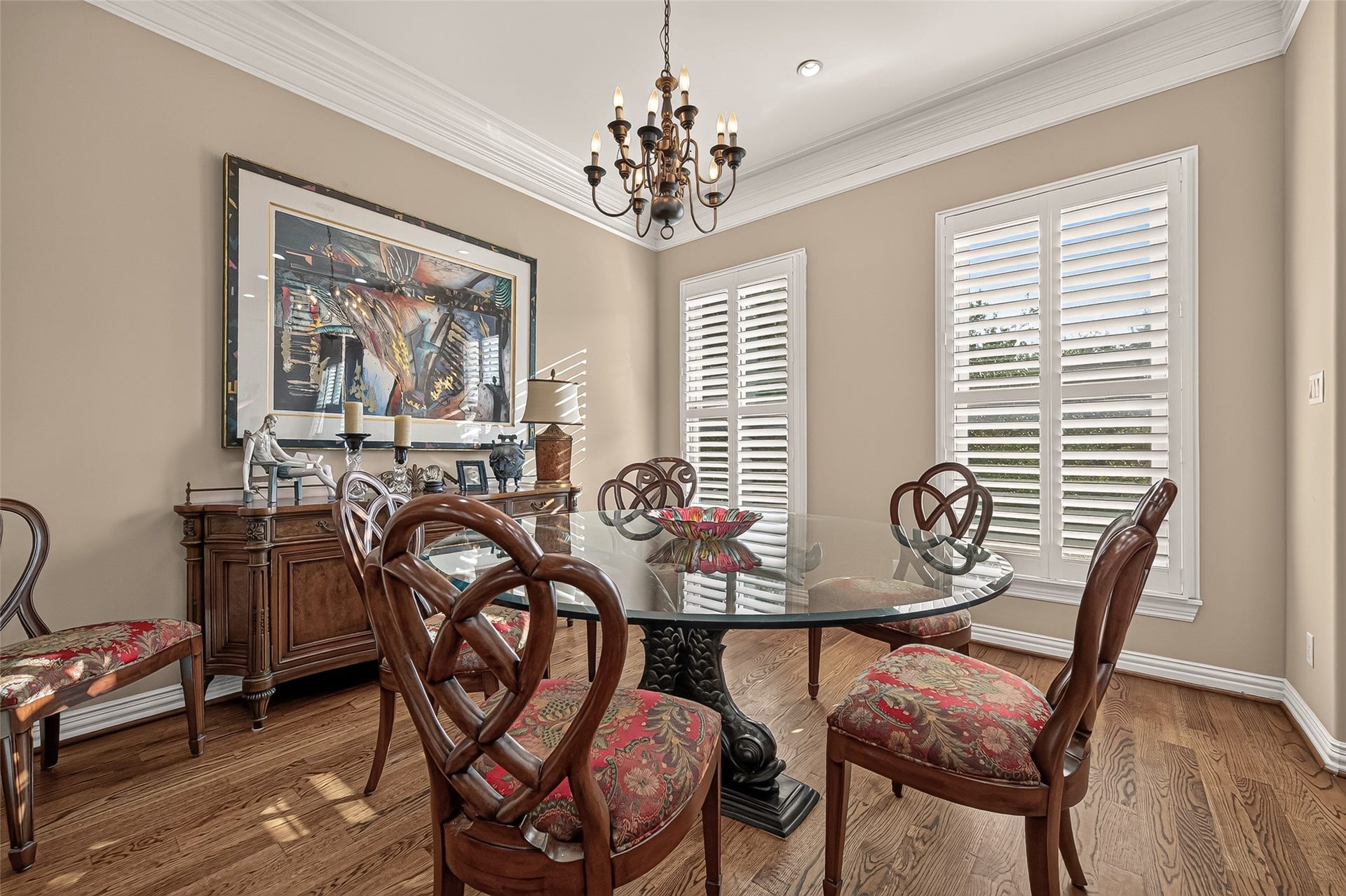 4003 Bellefontaine Street, Houston, TX 77025 Light-filled dining room featuring two tall windows with plantation shutters, rich hardwood floors, and detailed crown molding. A classic chandelier adds an elegant finishing touch to this welcoming space for gatherings.
