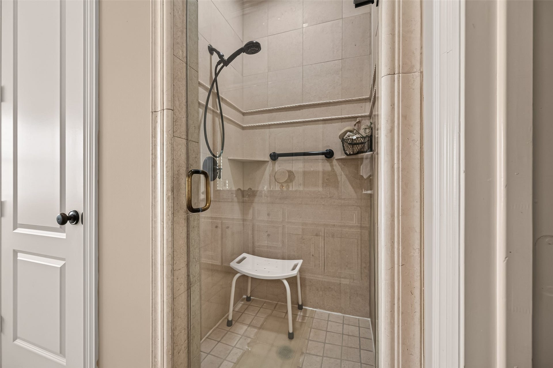 4003 Bellefontaine Street, Houston, TX 77025 Primary bathrooms separate glass-enclosed shower featuring elegant tilework, decorative trim, built-in corner shelves, and a handheld showerhead for added convenience.