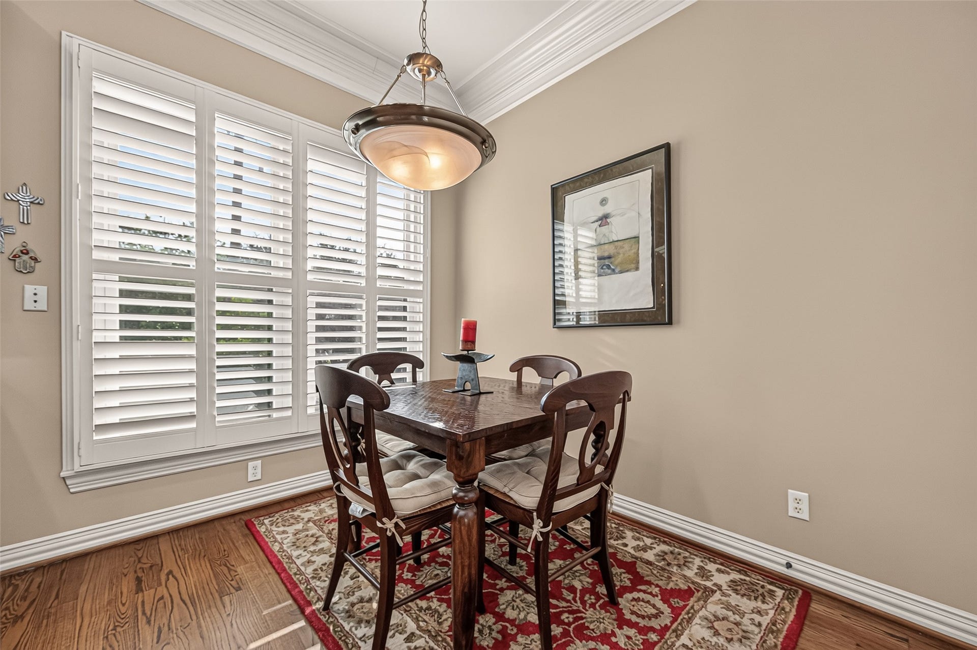 4003 Bellefontaine Street, Houston, TX 77025 Sunlit breakfast nook featuring expansive windows with plantation shutters, hardwood floors, and detailed crown molding. An elegant pendant light completes this inviting spot for morning coffee and casual dining.