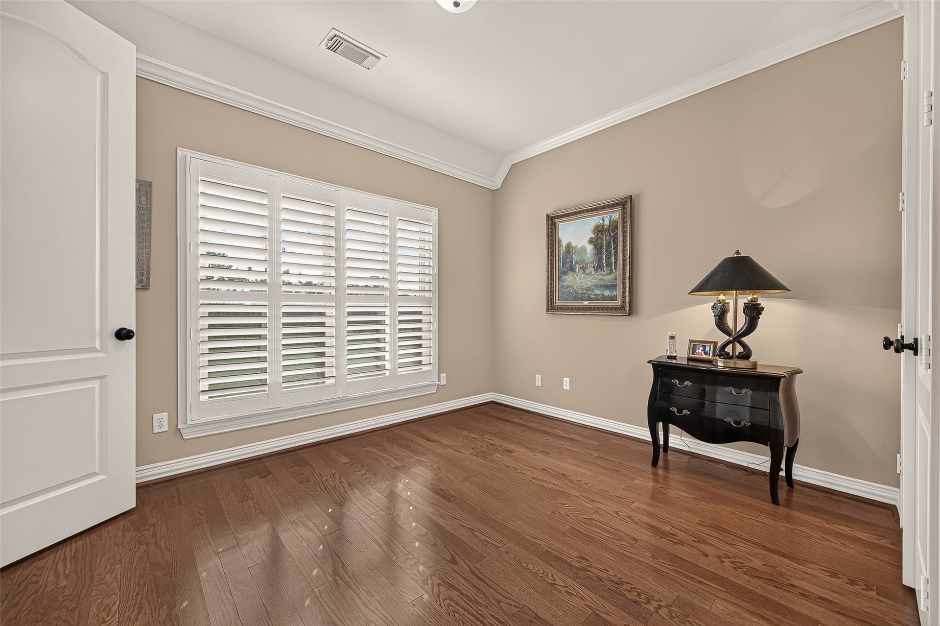 4003 Bellefontaine Street, Houston, TX 77025 Bright third-floor secondary bedroom featuring rich hardwood floors, high ceilings, and crown molding. A large window with plantation shutters brings in natural light, creating a comfortable retreat for family or guests.