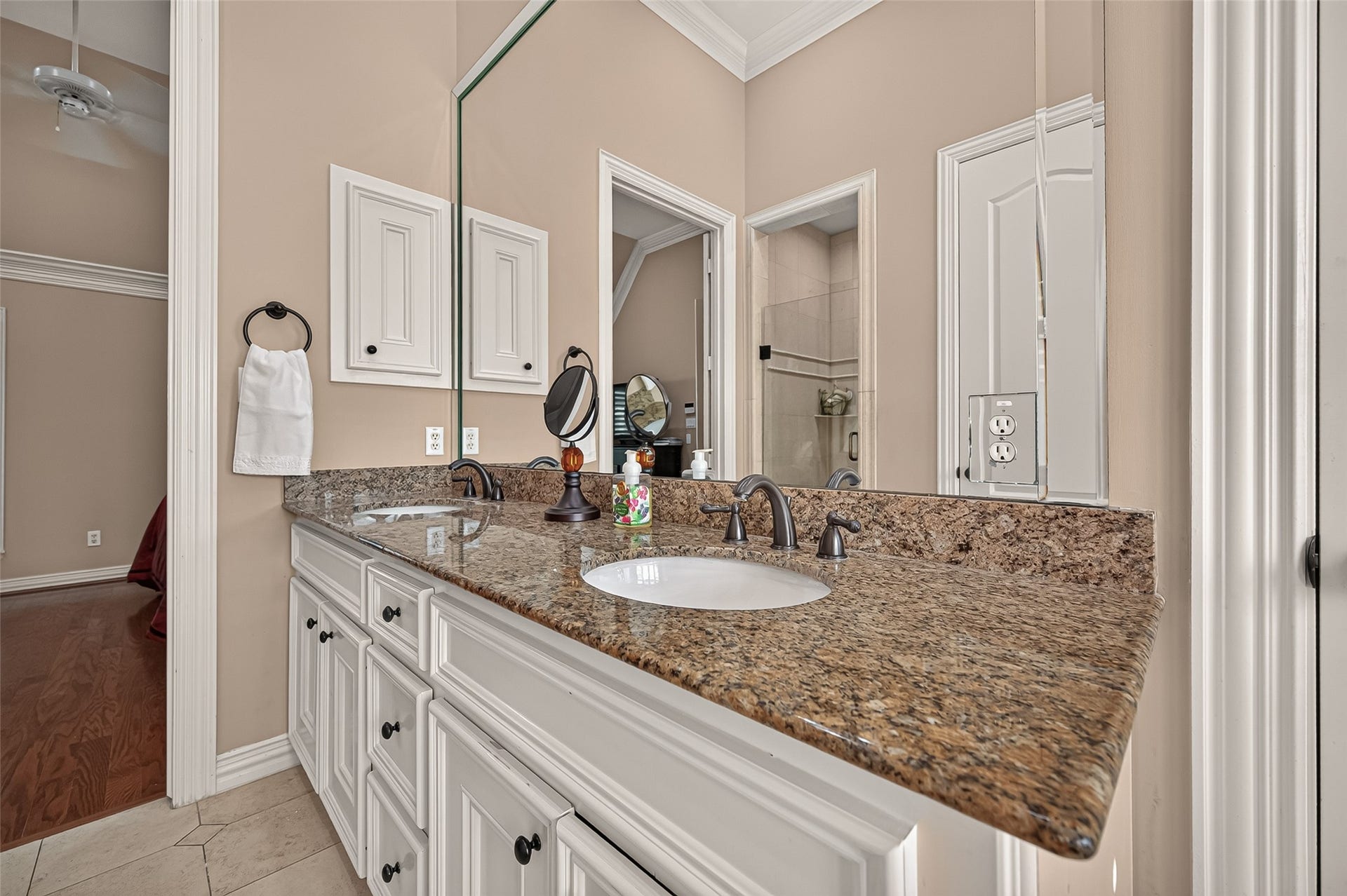 4003 Bellefontaine Street, Houston, TX 77025 They appear to be oil-rubbed bronze, though the exact finish is difficult to confirm from the photo.
Primary bathroom vanity featuring expansive granite countertops, dual undermount sinks, and ample cabinet and drawer storage. A wall-spanning mirror and elegant fixtures complete this refined space.