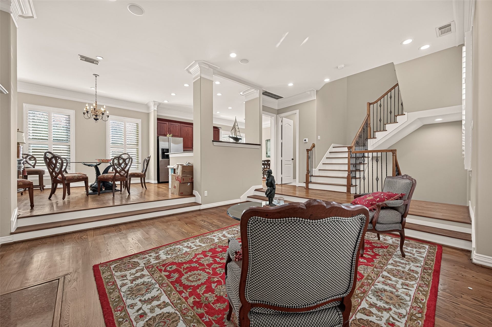 4003 Bellefontaine Street, Houston, TX 77025 Elegant second-floor living area featuring hardwood floors, crown molding, and recessed lighting. Architectural columns frame the raised dining area, while plantation shutters and an open connection to the kitchen create an inviting setting for entertaining.