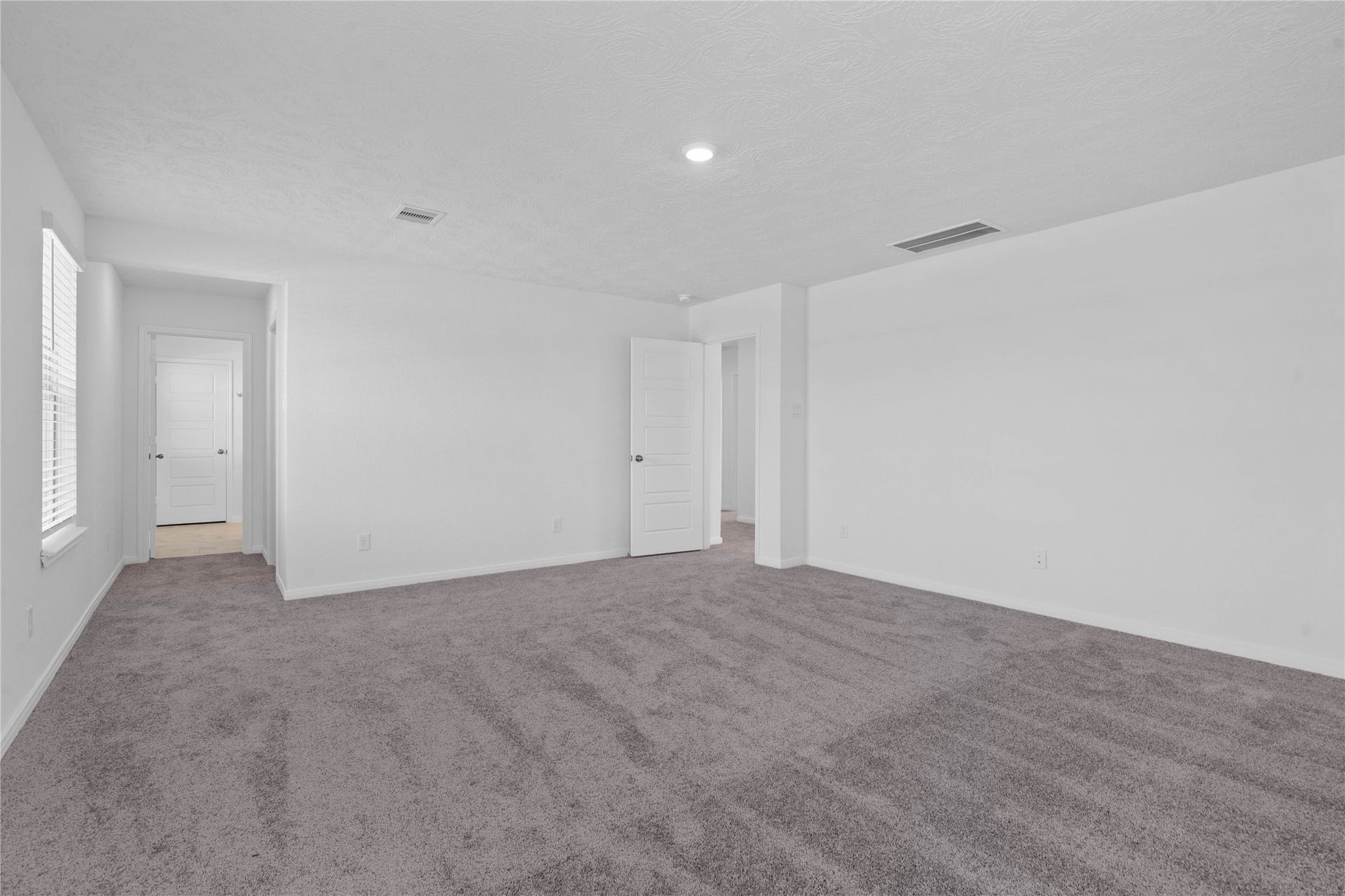 Come and unwind after a long day in this magnificent and spacious primary suite! This room features plush carpet, neutral paint, high ceiling, and large windows fitted with blinds.