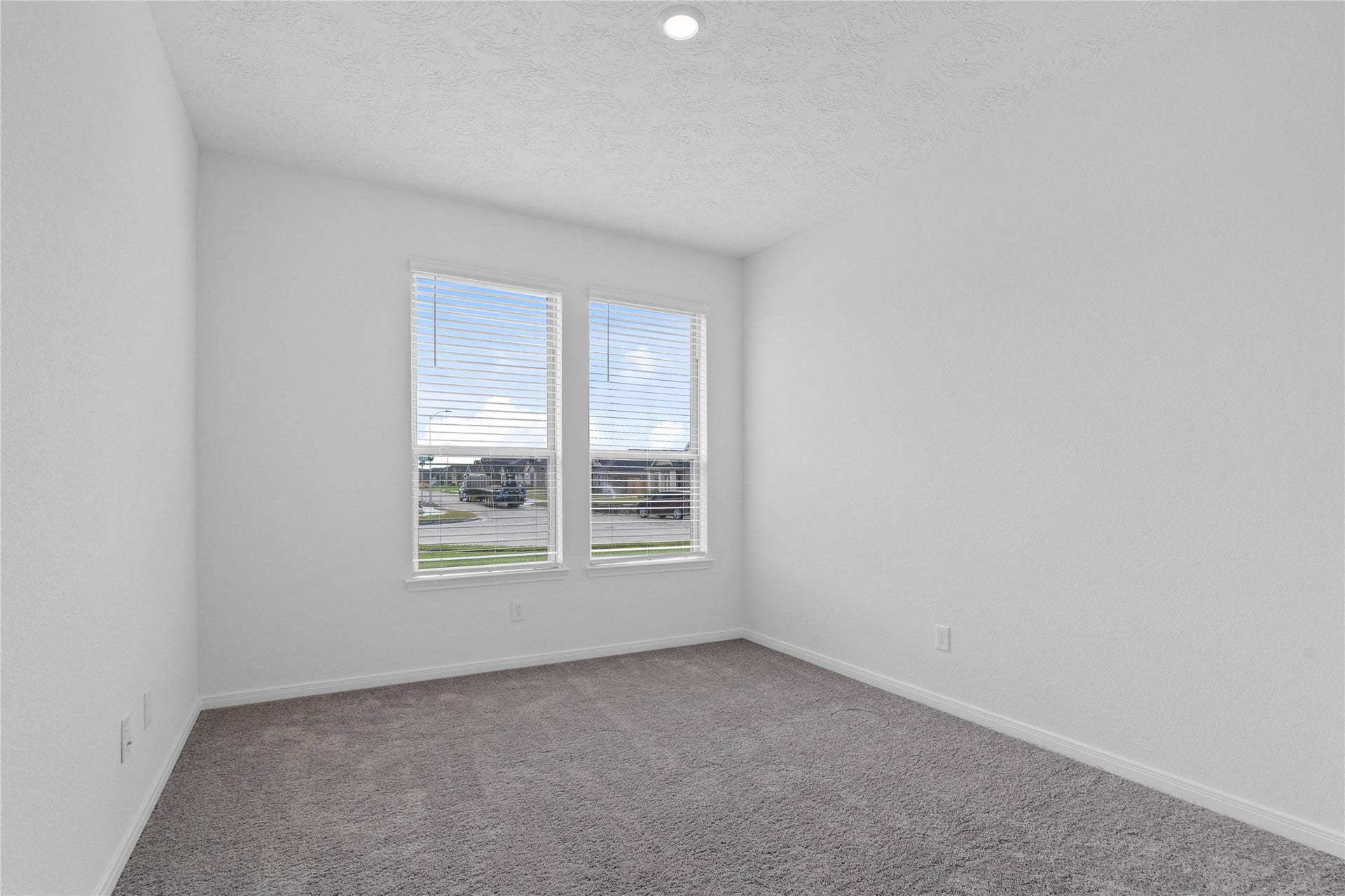 Quietly nestled in front of the home is the handsome Den featuring plush carpet flooring, high ceilings, large windows with privacy blinds and neutral paint.