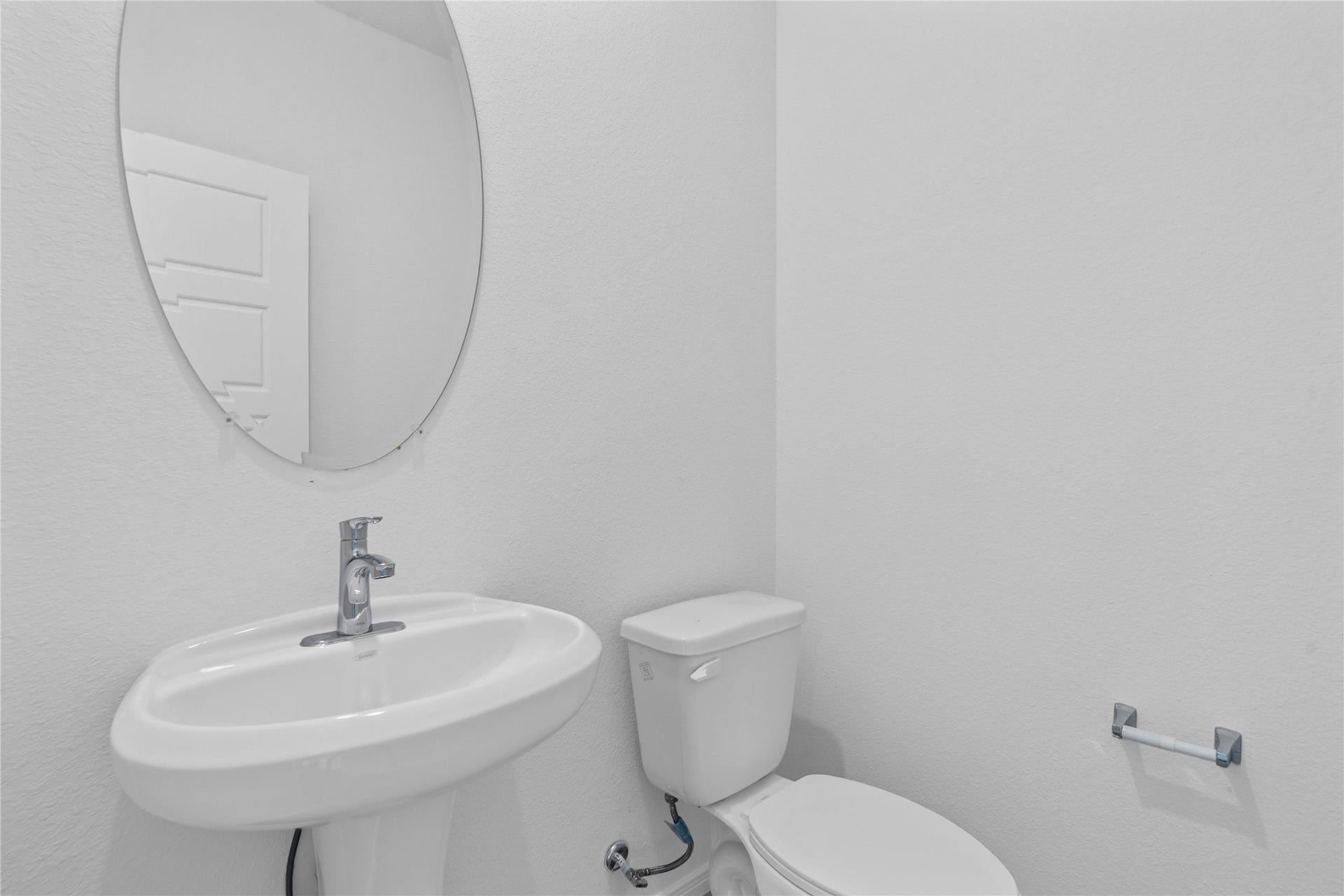 The powder bathroom features vinyl plank flooring, custom paint, pedestal sink with Moen faucet, and oval mirror.
