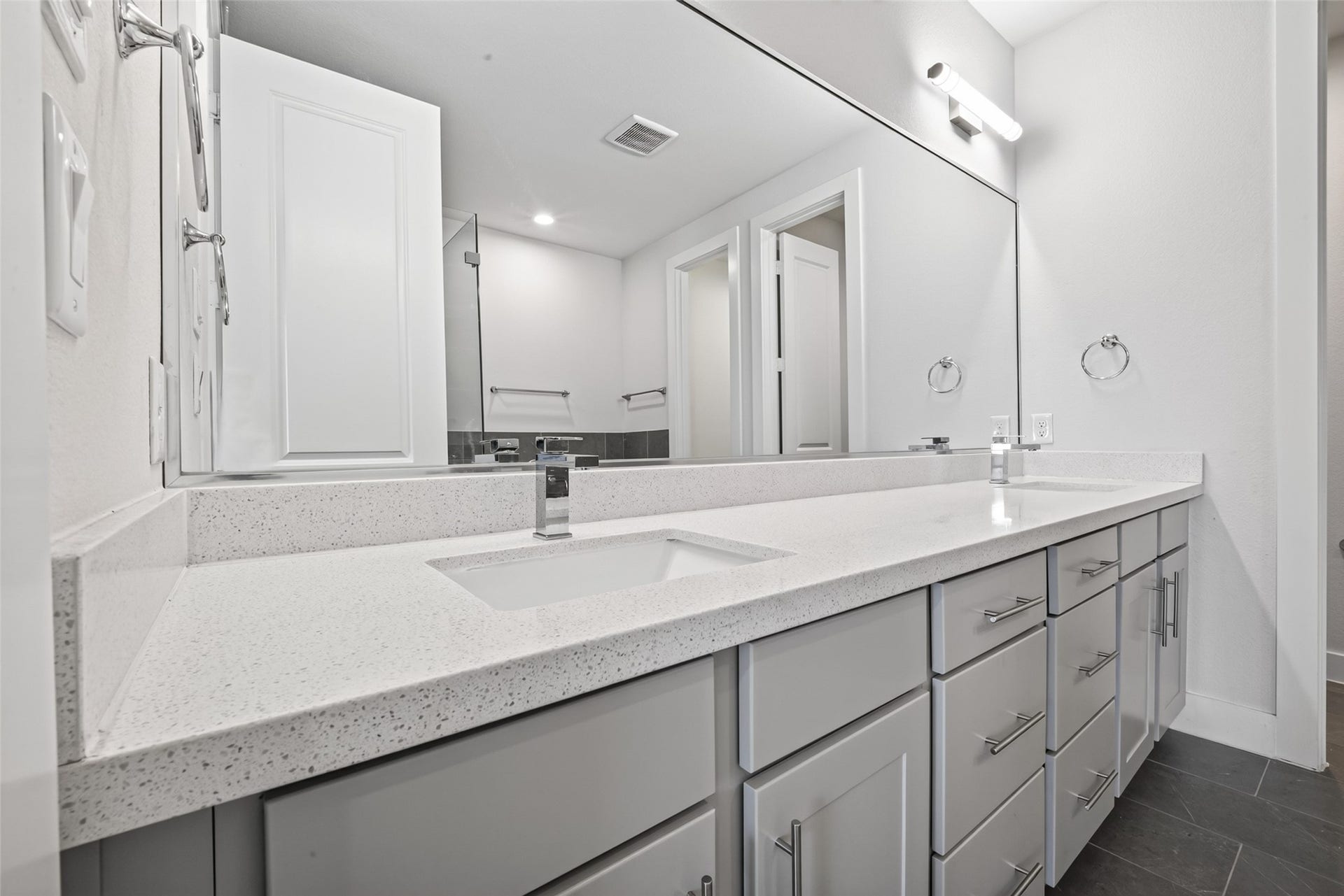 Sleek bathroom featuring a long, dual-sink vanity with modern fixtures, ample storage, and a large, well-lit mirror.