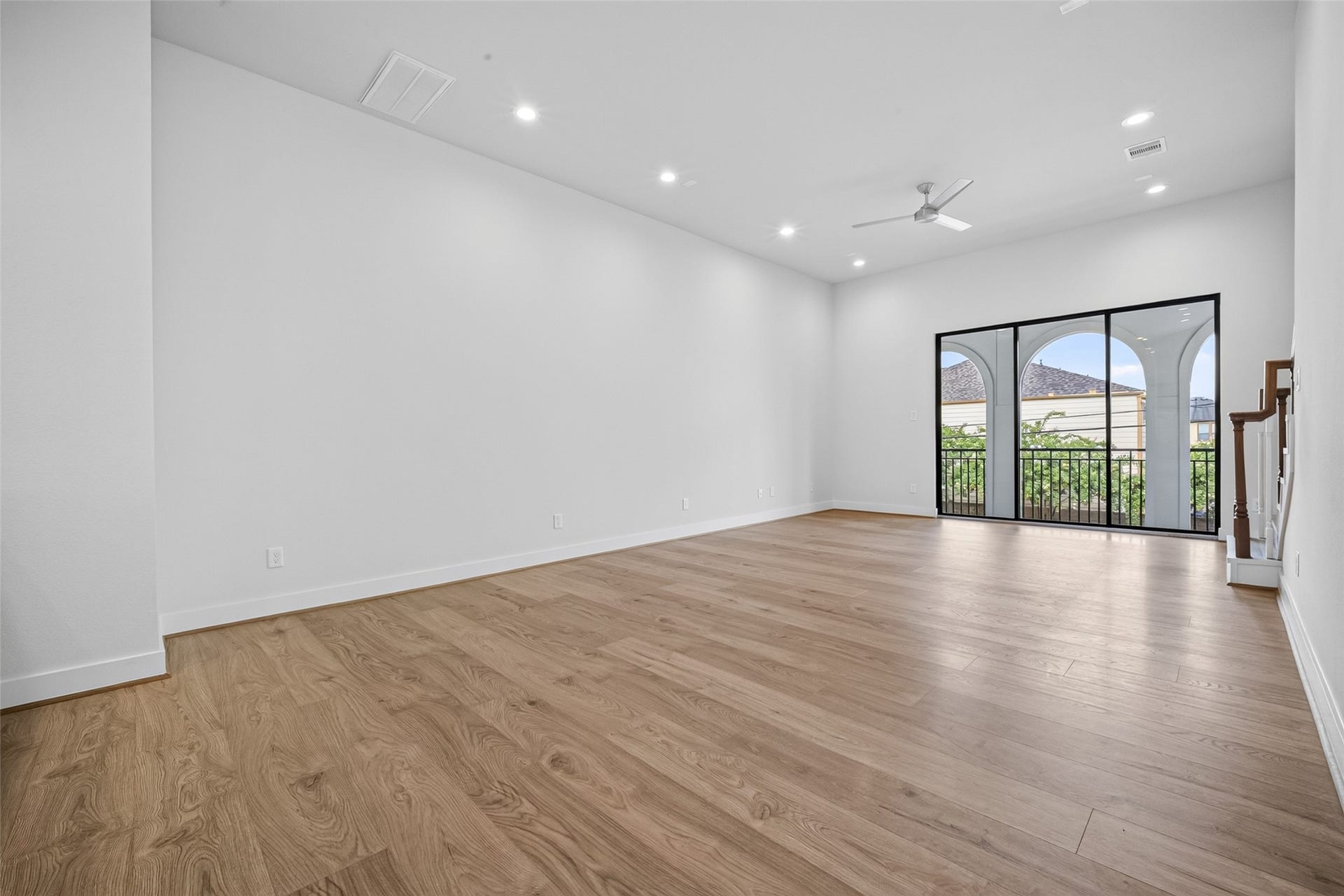 Spacious and bright living area with sleek LVP floors, high ceilings, and large windows opening to a balcony, offering abundant natural light and a modern feel.
